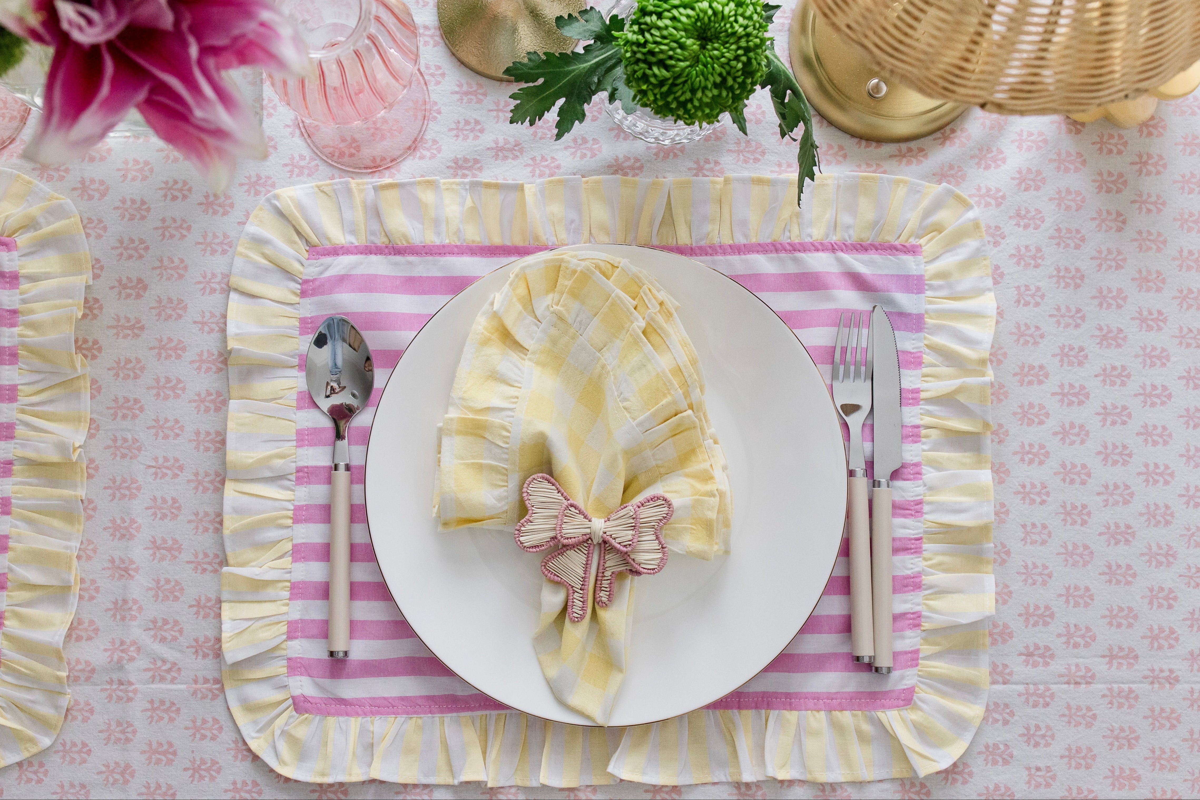 Soft pastel striped cotton placemats in pink and yellow with delicate frilled edges styled for a cottagecore garden brunch
