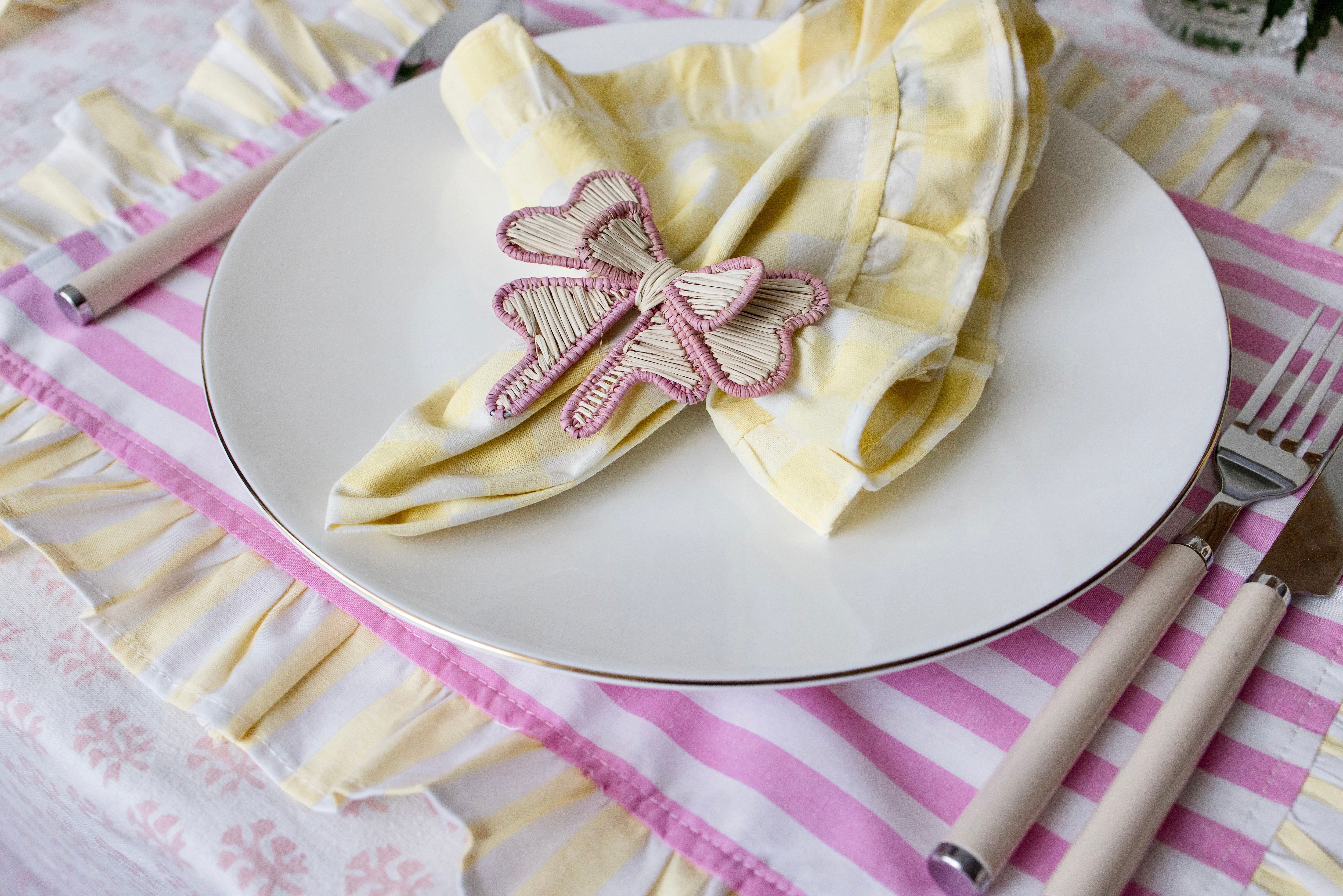 Soft pastel striped cotton placemats in pink and yellow with delicate frilled edges styled for a cottagecore garden brunch