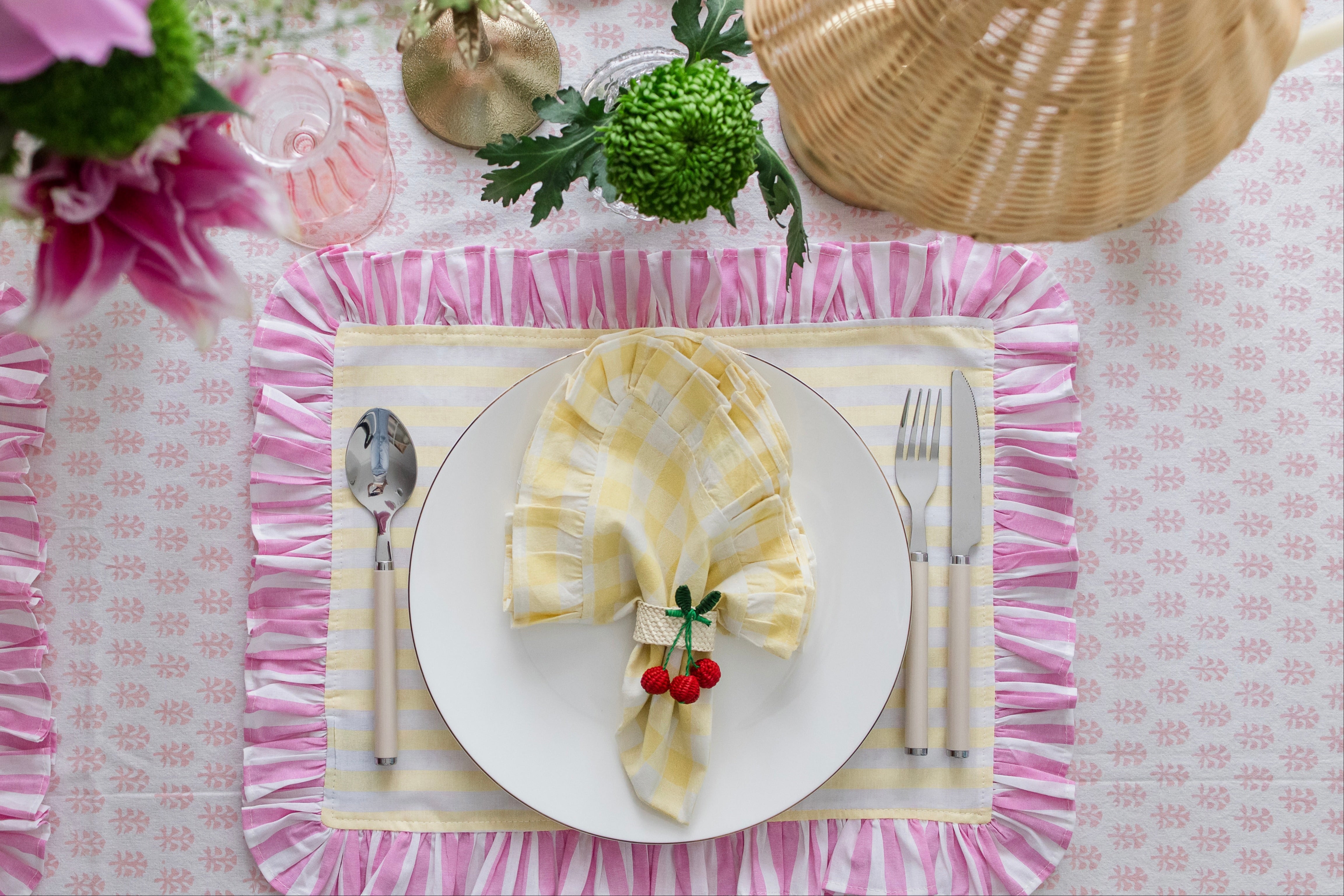 Soft pastel striped cotton placemats in yellow and pink with delicate frilled edges styled for a cottagecore garden brunch