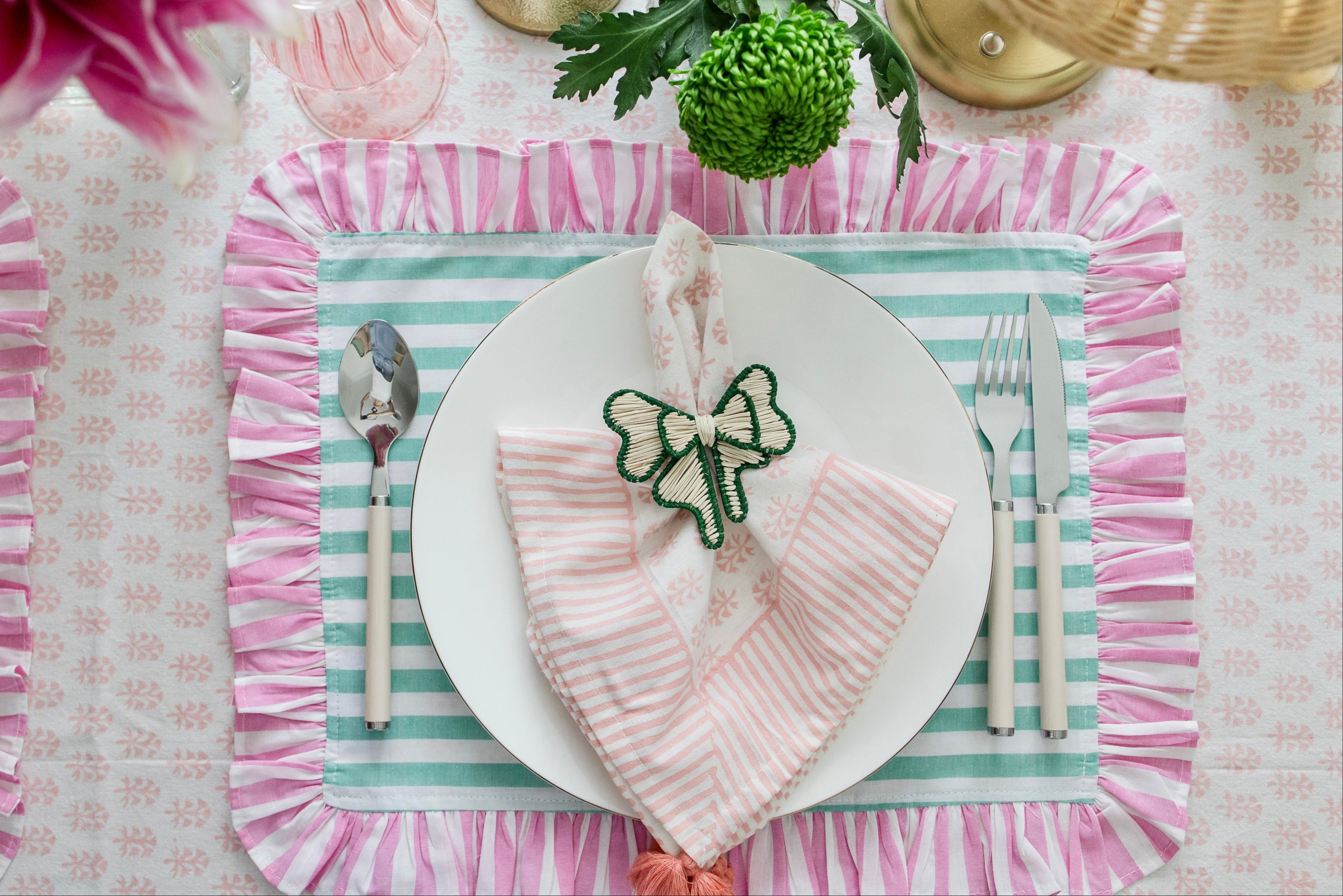 Soft pastel striped cotton placemats in green and pink with delicate frilled edges styled for a cottagecore garden brunch