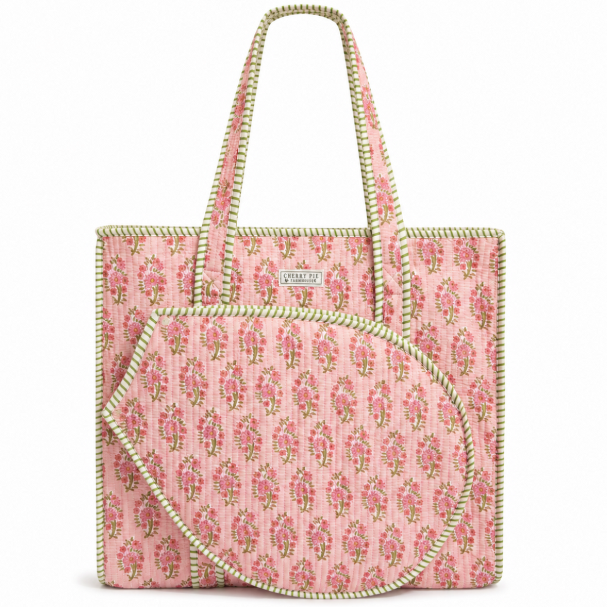A pink quilted fabric tote bag with a repeating floral pattern, featuring light green braided trim and handles, shown on a plain white background.