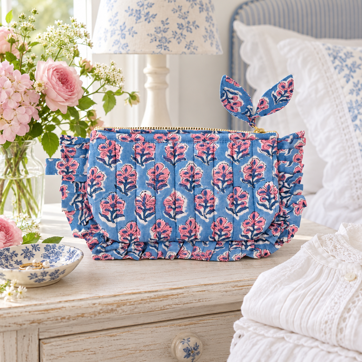 Dusty blue and pink floral frill pouch styled on an airy cottage bedside table