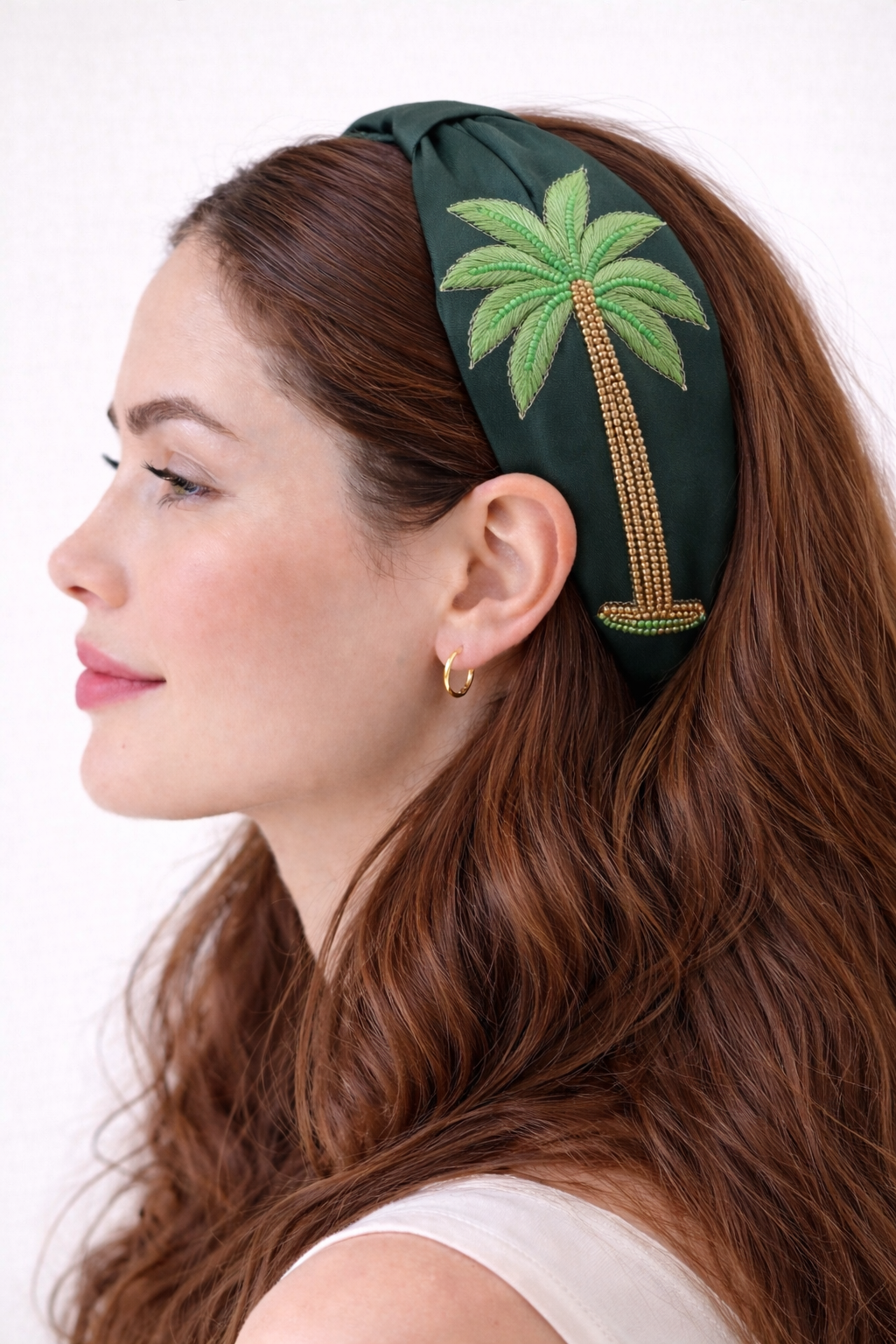 Woman wearing a green headband with palm tree design on a white background