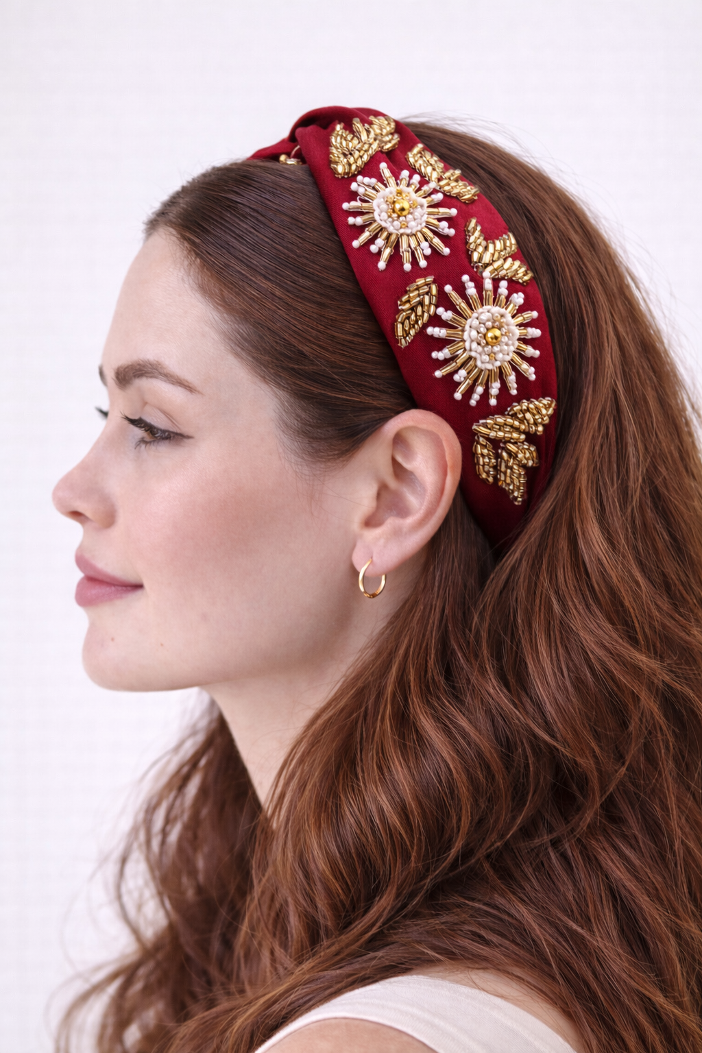 Woman wearing a decorative red headband with gold embellishments on a white background