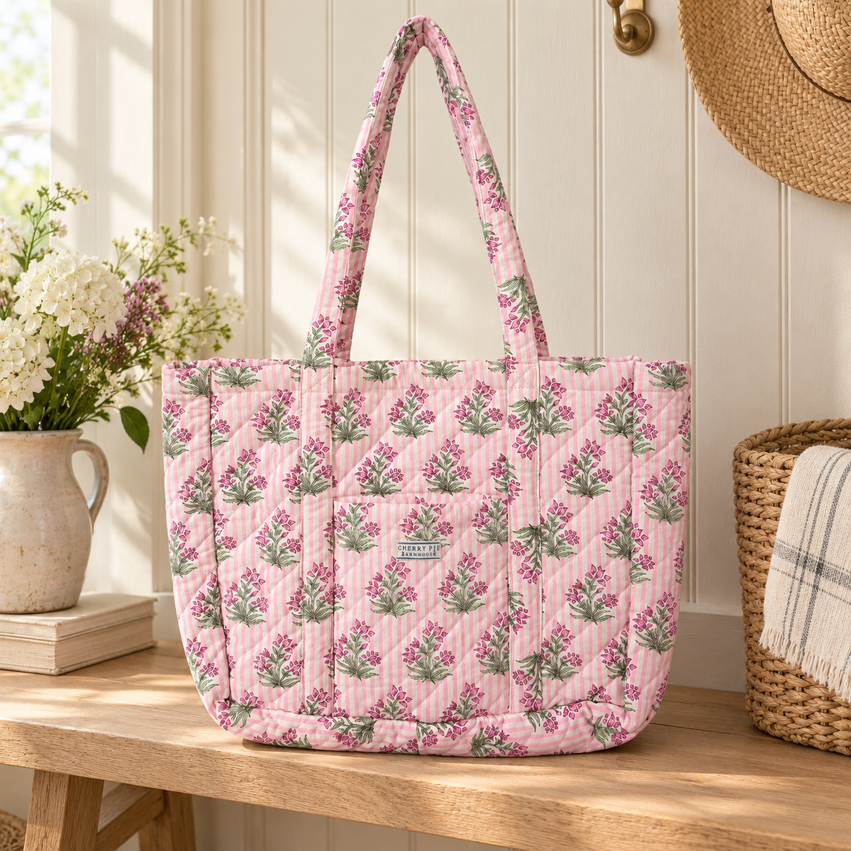 Pink striped quilted floral tote bag styled on a pale wood bench in a light farmhouse entryway.