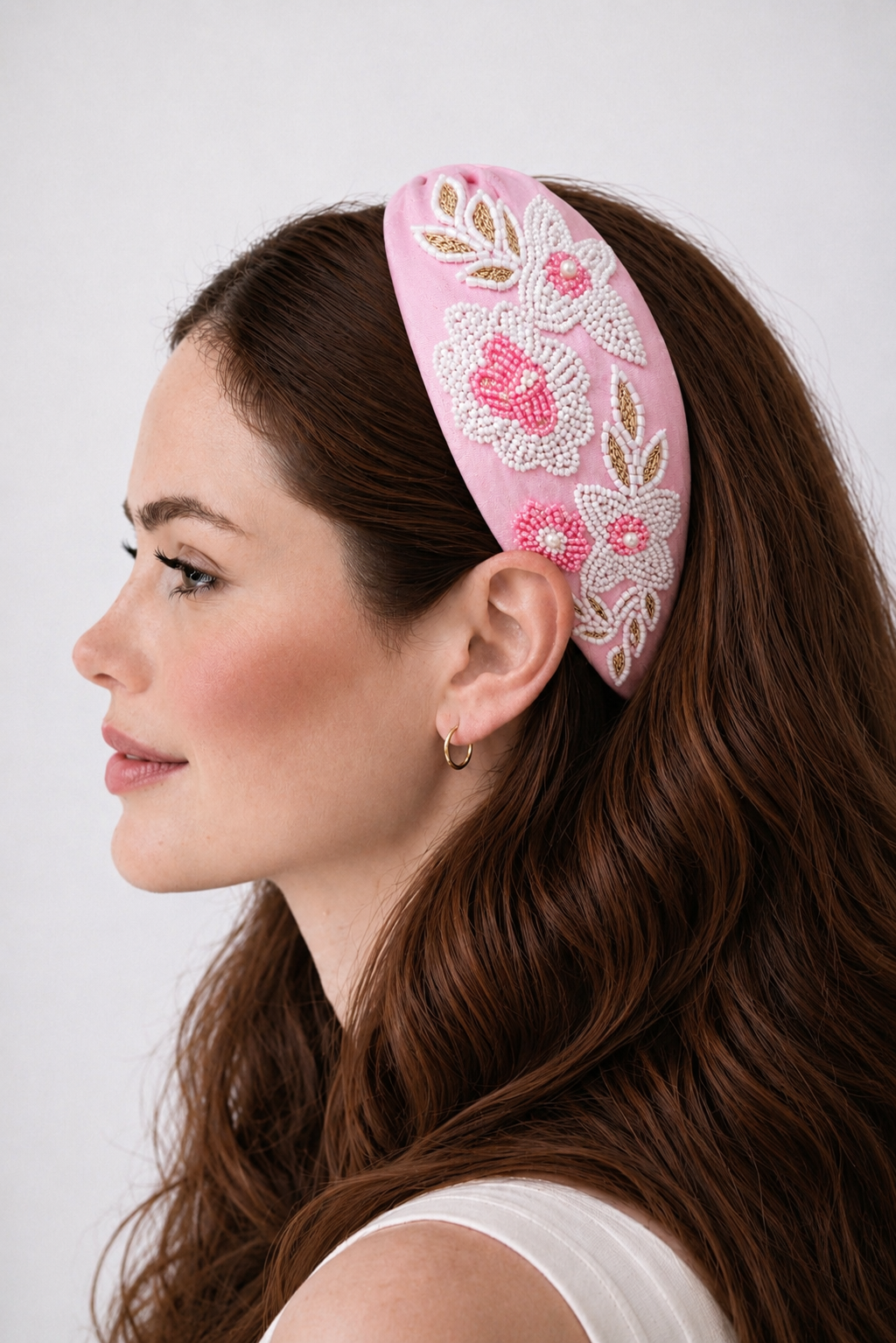 Woman wearing a pink headband with floral embroidery on a white background