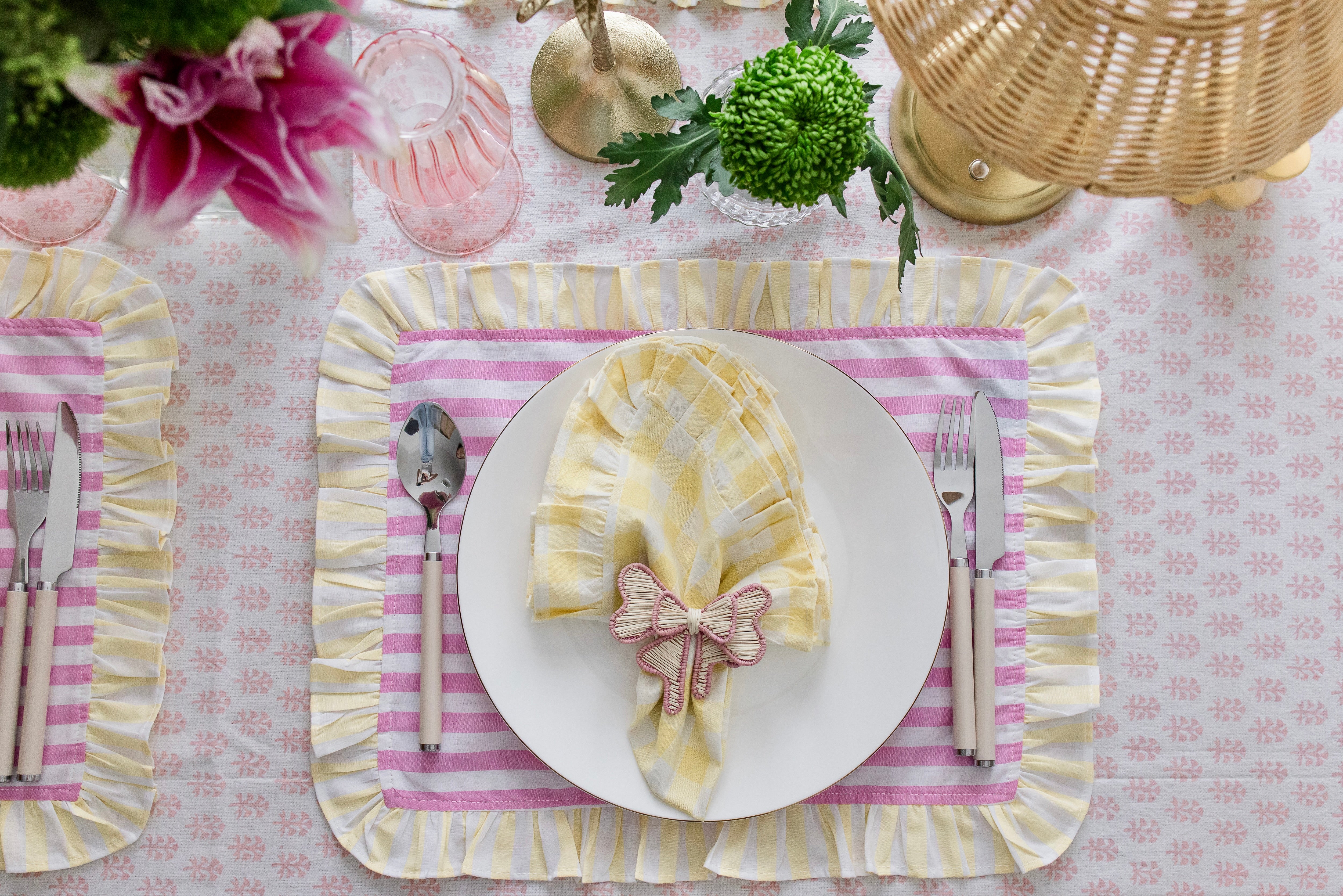 Handcrafted iraca palm bow napkin rings in pink wrapped around linen napkins on table