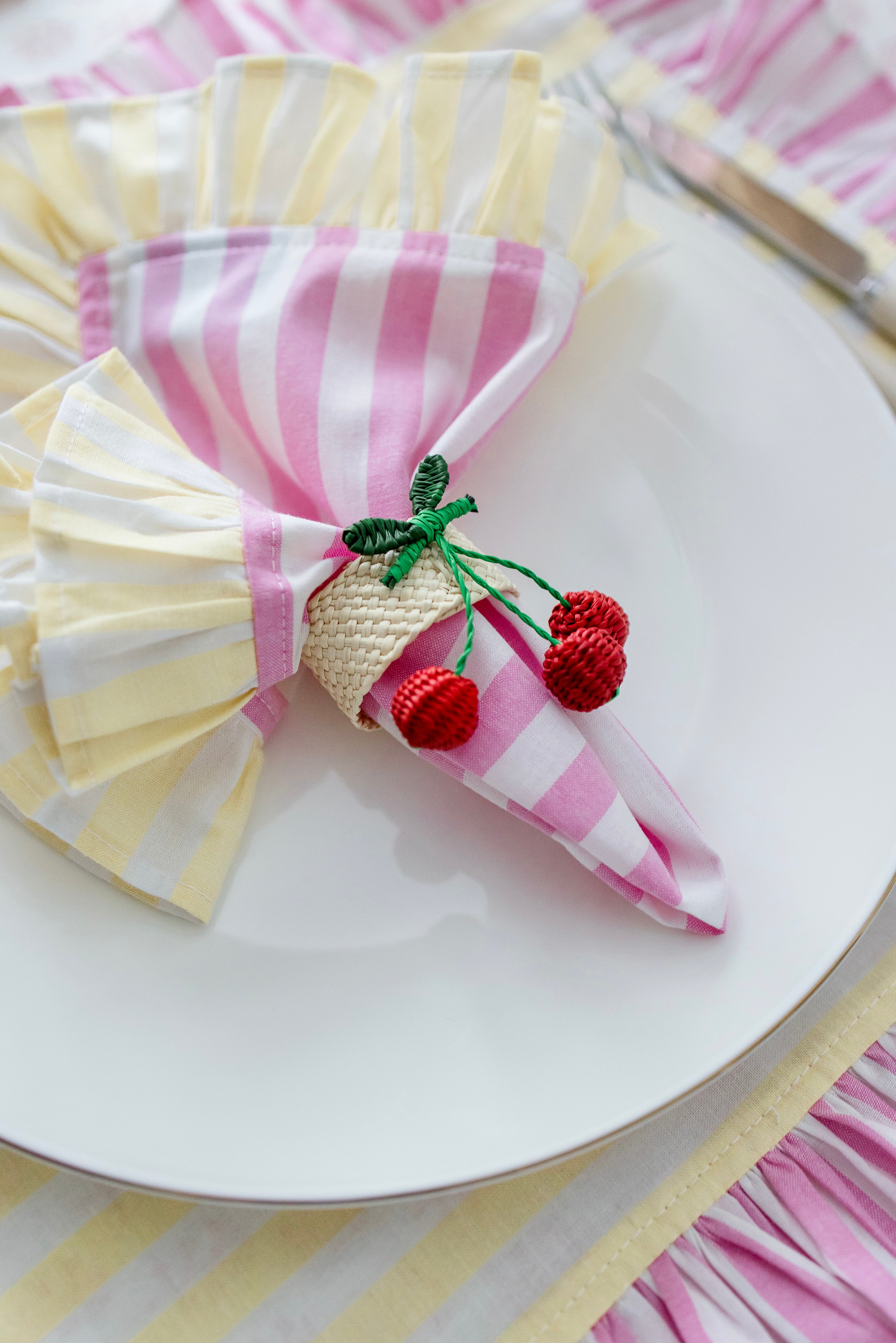 Handcrafted iraca palm cherry napkin rings wrapped around linen napkins on table