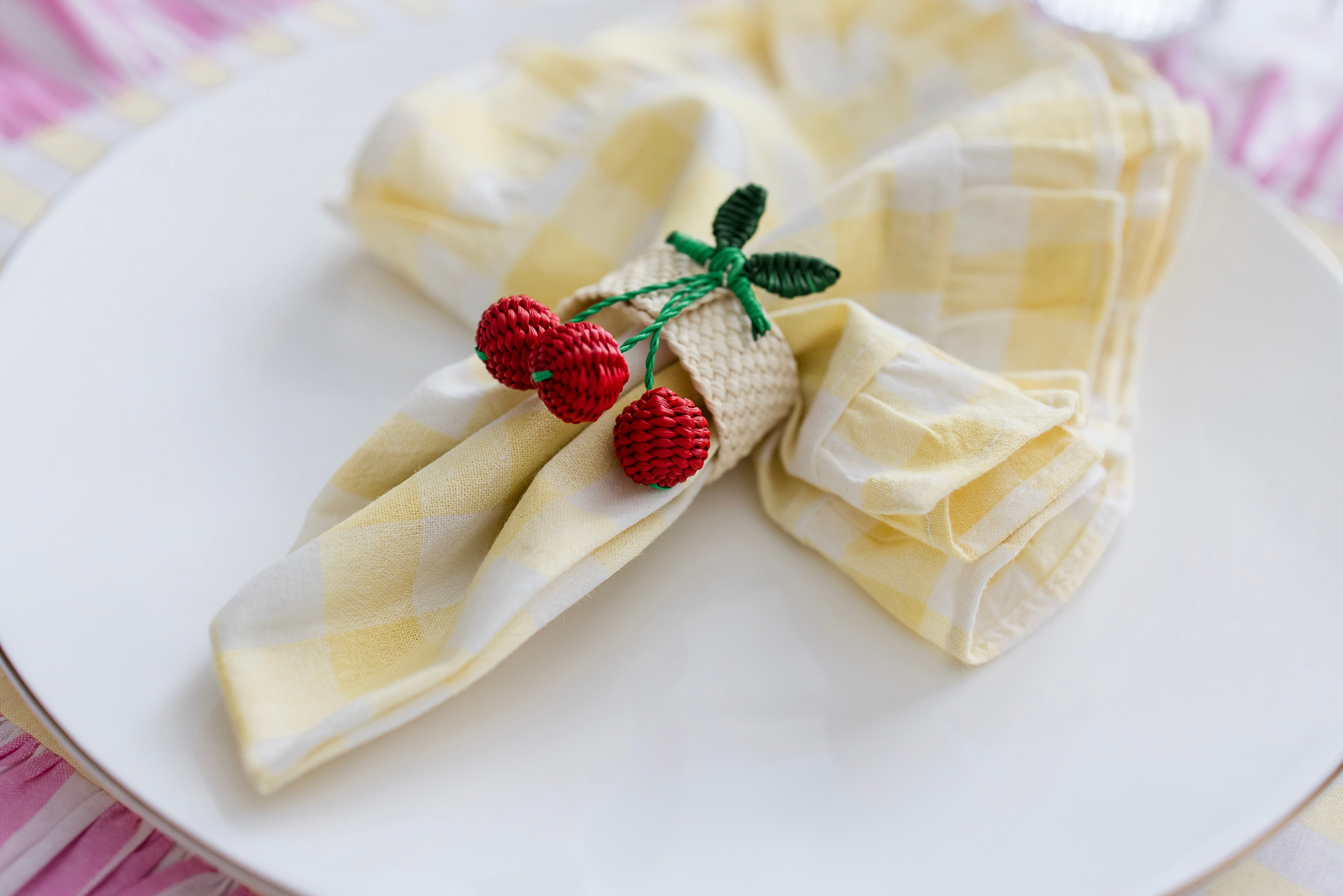 Handcrafted iraca palm cherry napkin rings wrapped around linen napkins on table