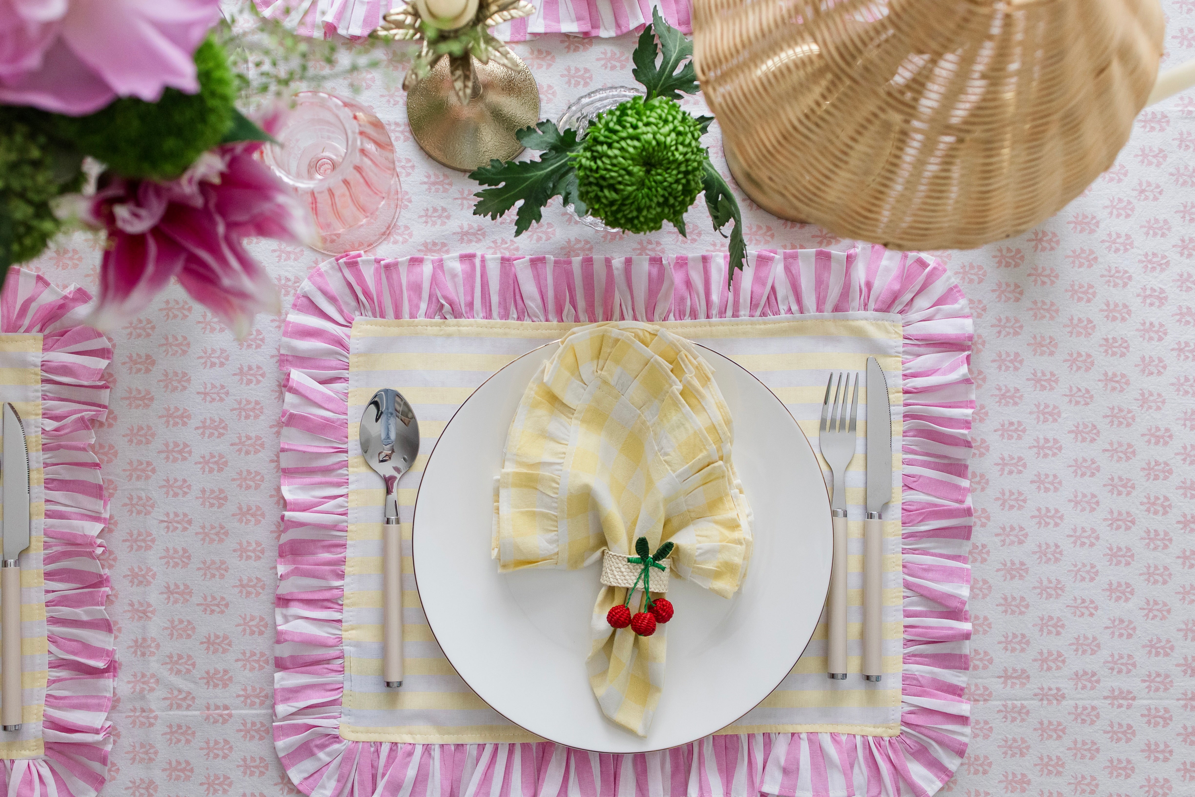 Handcrafted iraca palm cherry napkin rings wrapped around linen napkins on table