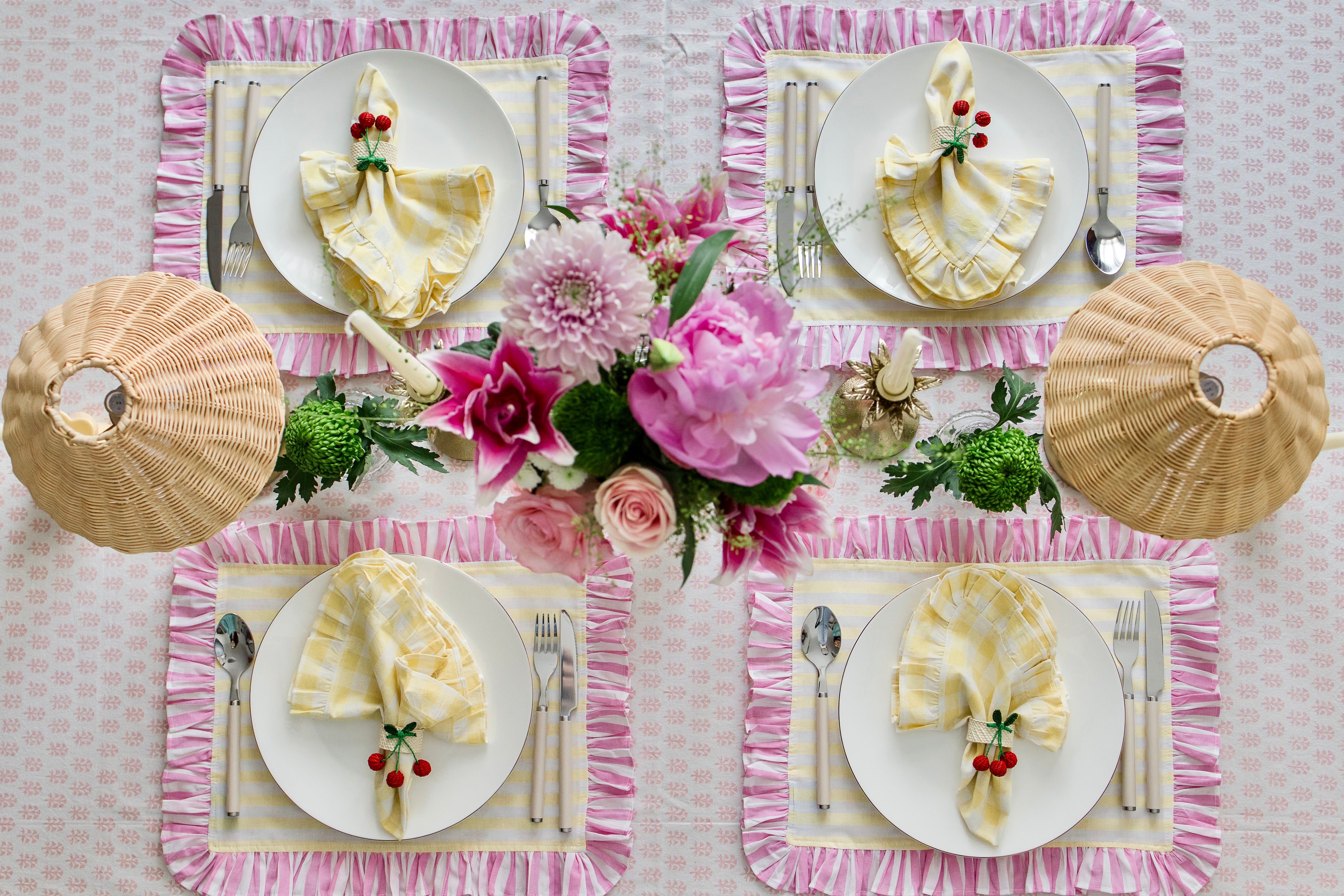 Handcrafted iraca palm cherry napkin rings wrapped around linen napkins on table