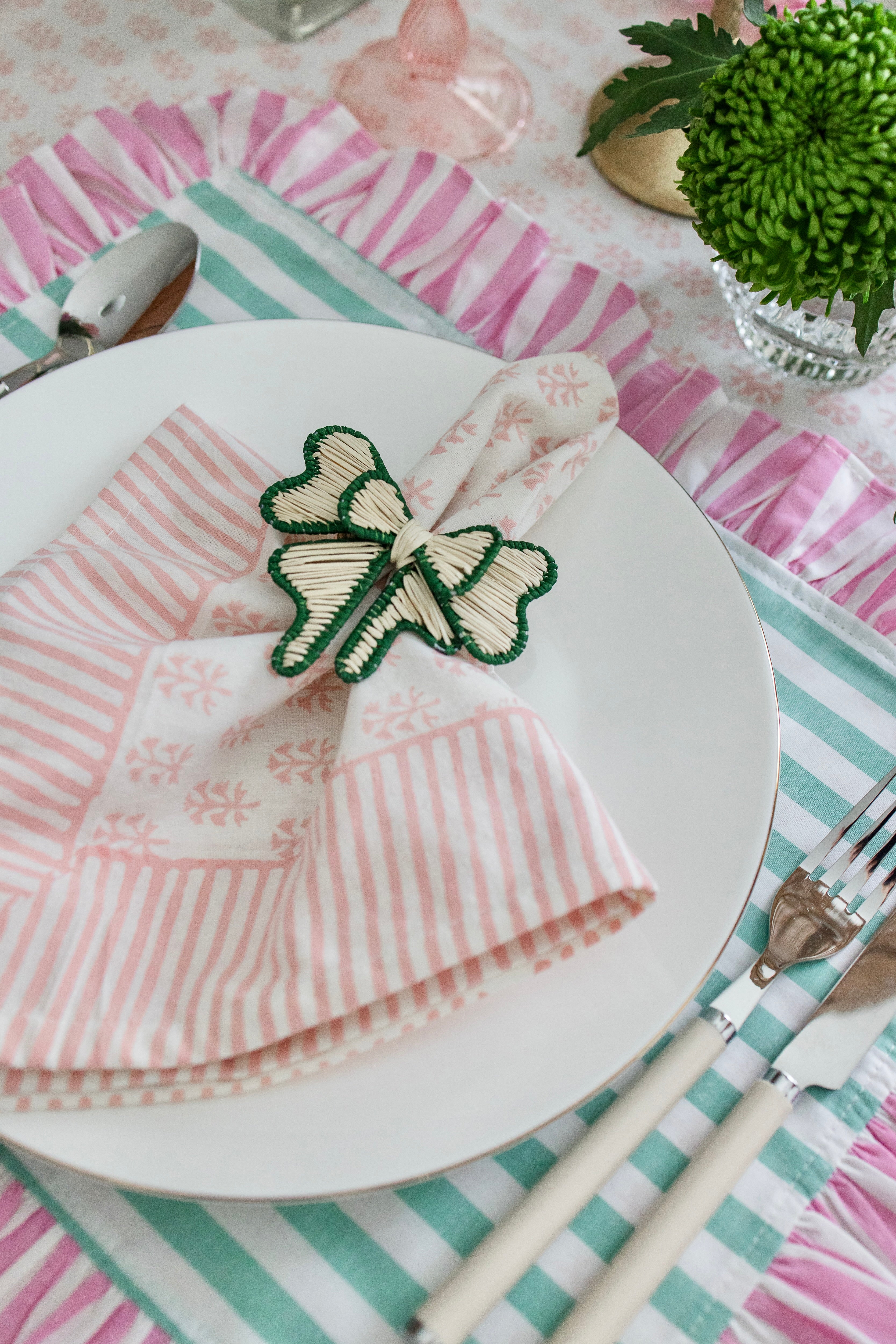 Handcrafted iraca palm bow napkin rings in green wrapped around linen napkins on table
