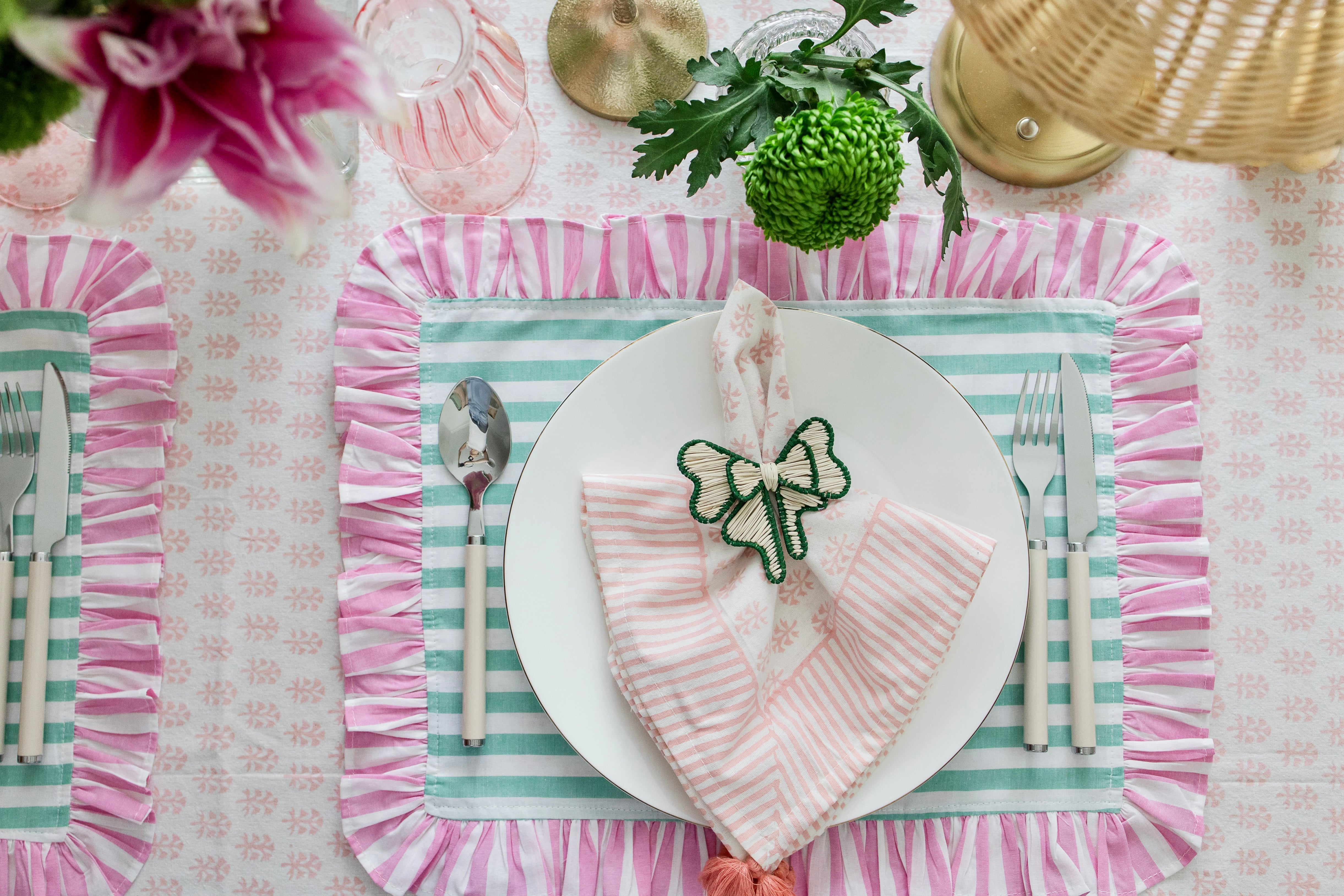 Handcrafted iraca palm bow napkin rings in green wrapped around linen napkins on table