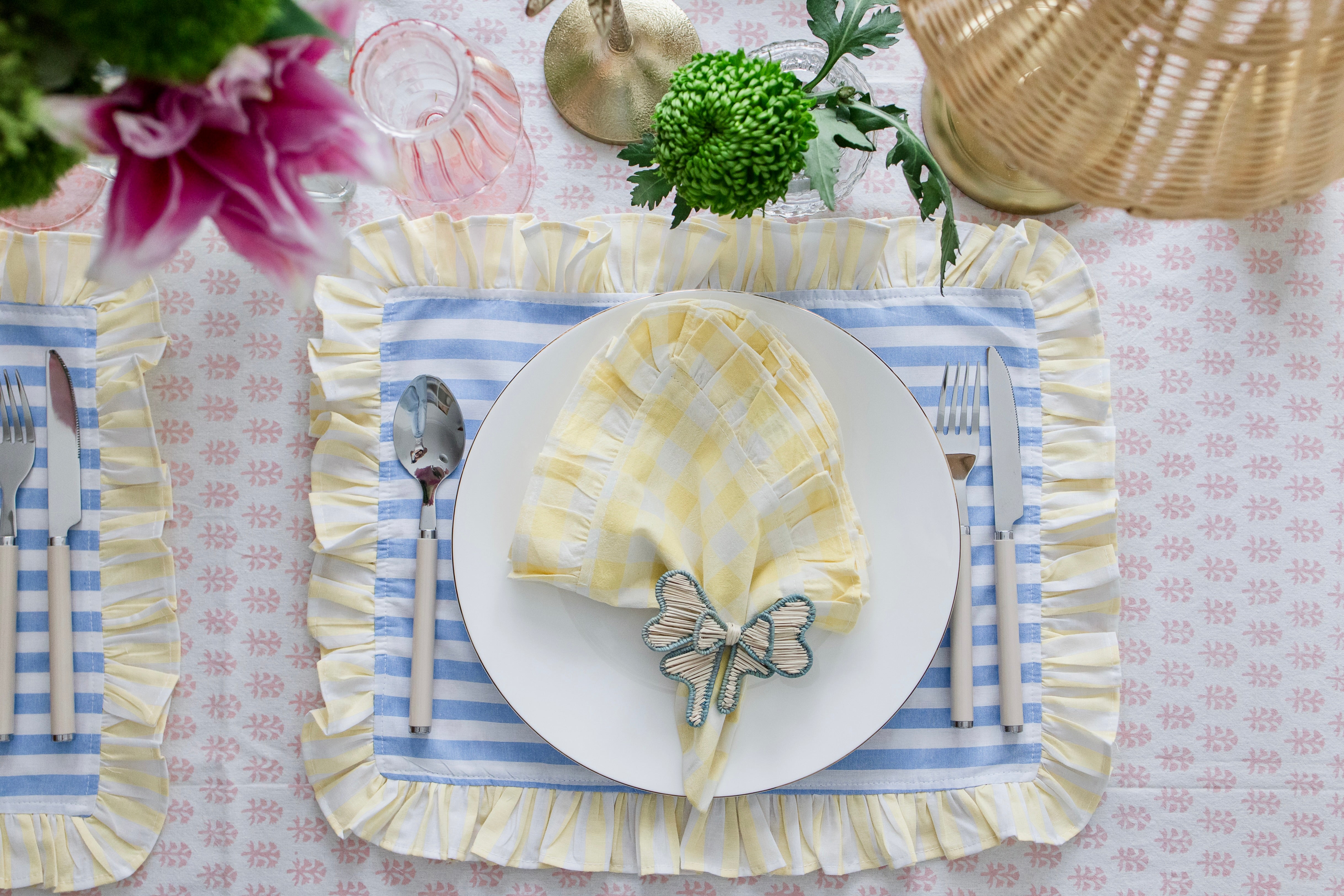 Handcrafted iraca palm bow napkin rings in blue wrapped around linen napkins on table