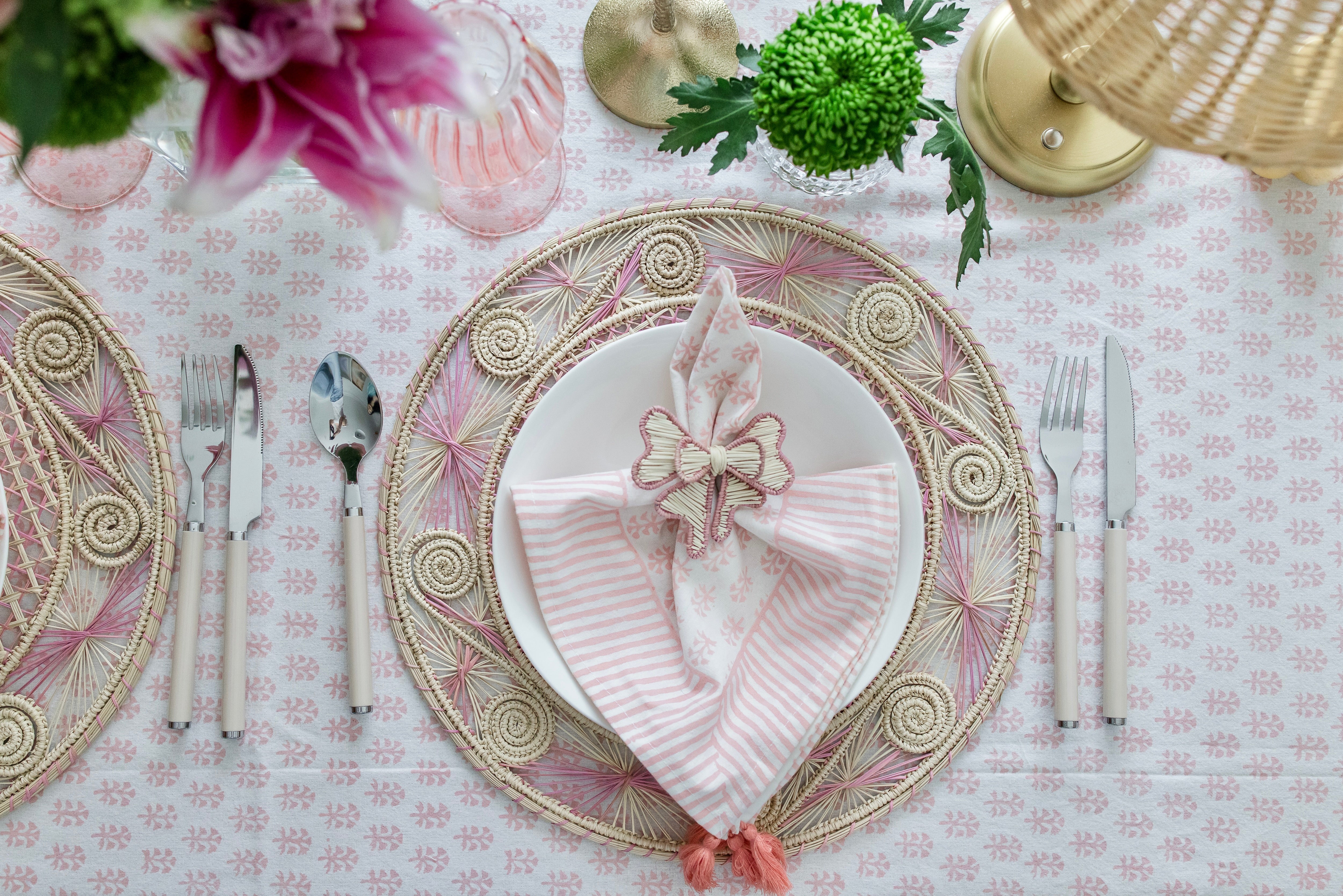 Round handwoven iraca palm placemats in Pink adding natural farmhouse texture to a rustic wooden table setting