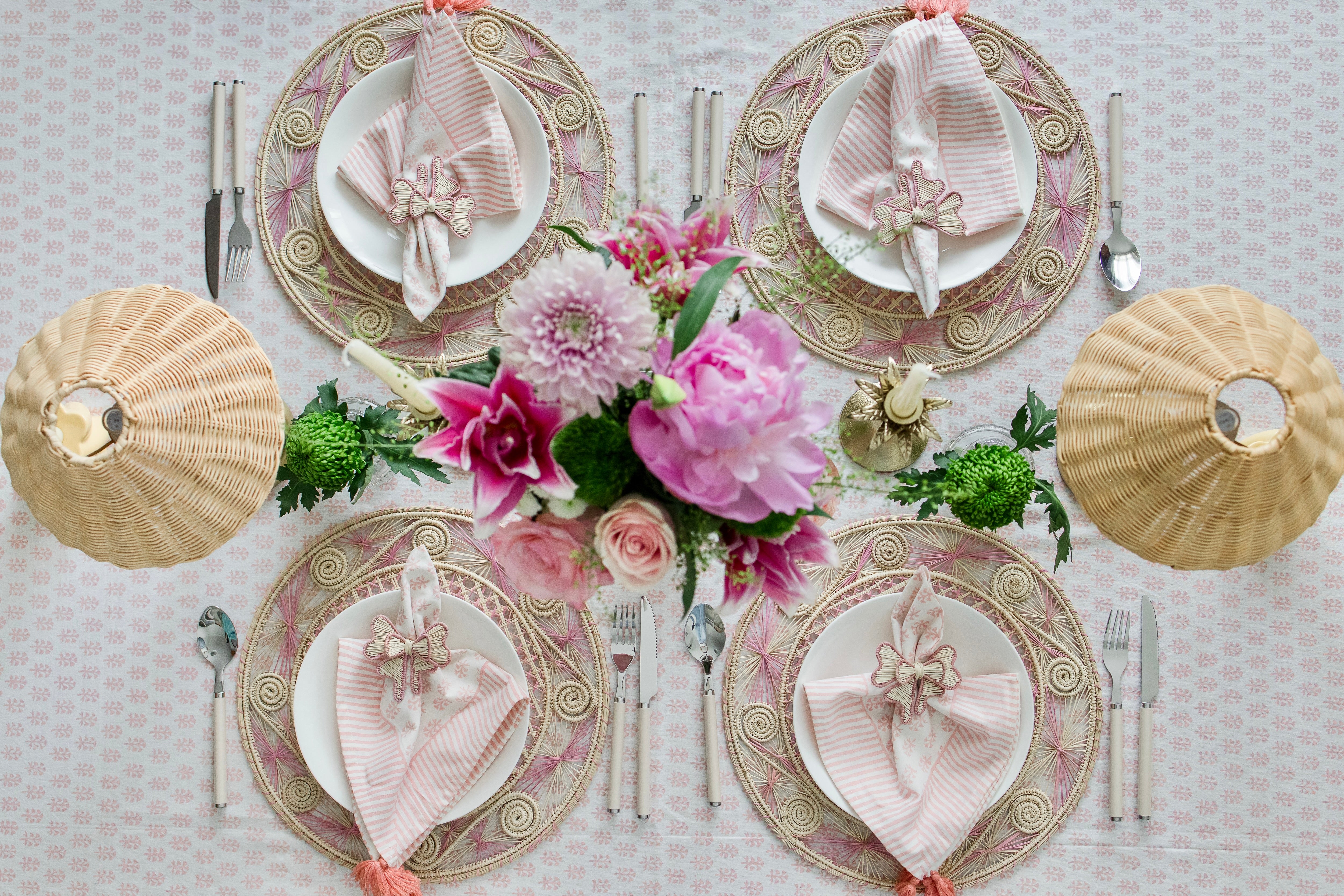 Round handwoven iraca palm placemats in Pink adding natural farmhouse texture to a rustic wooden table setting
