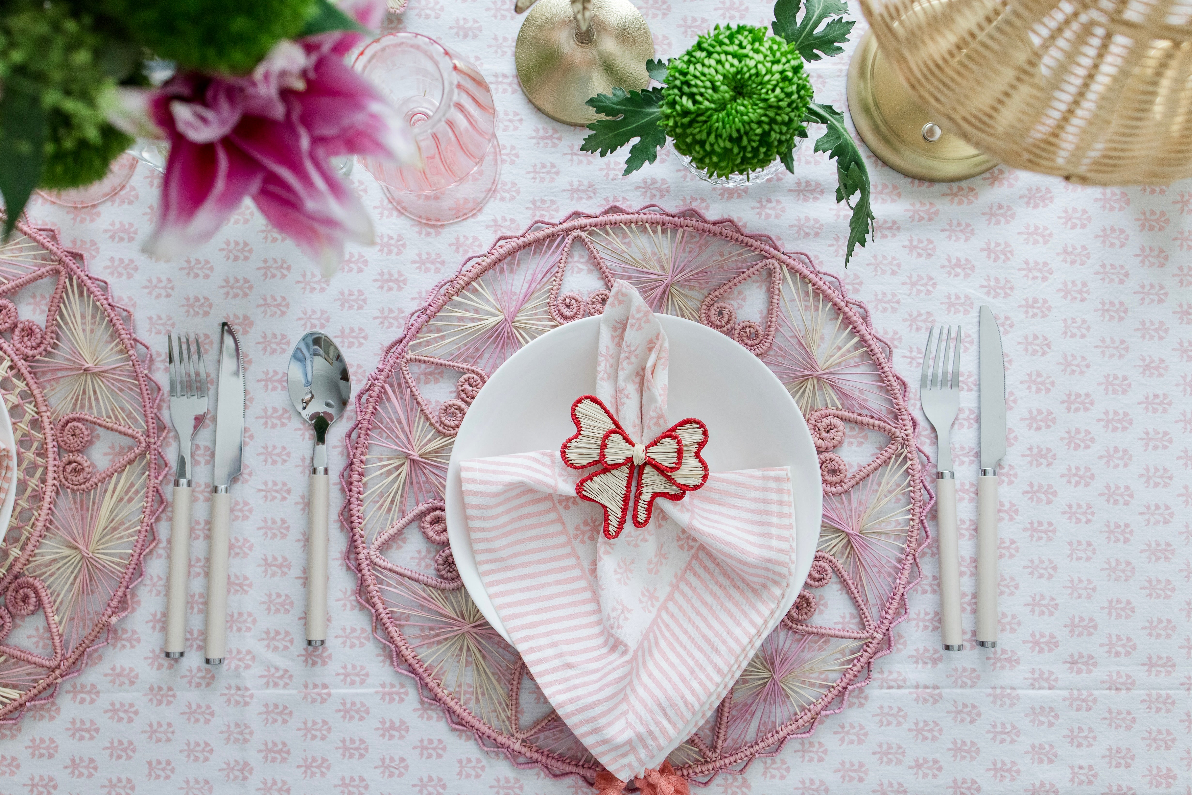 Handcrafted iraca palm bow napkin rings in red wrapped around linen napkins on table