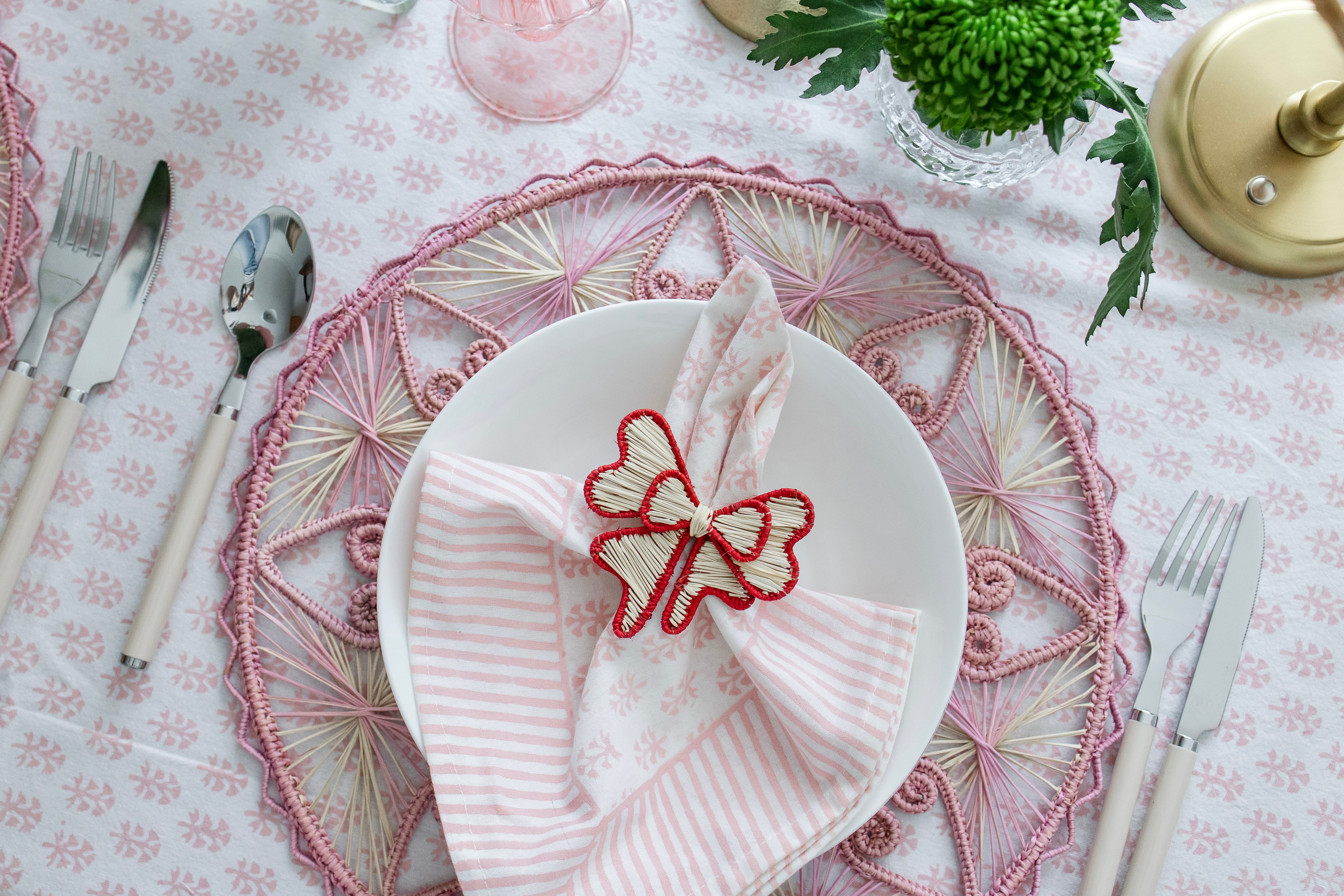 Handcrafted iraca palm bow napkin rings in red wrapped around linen napkins on table