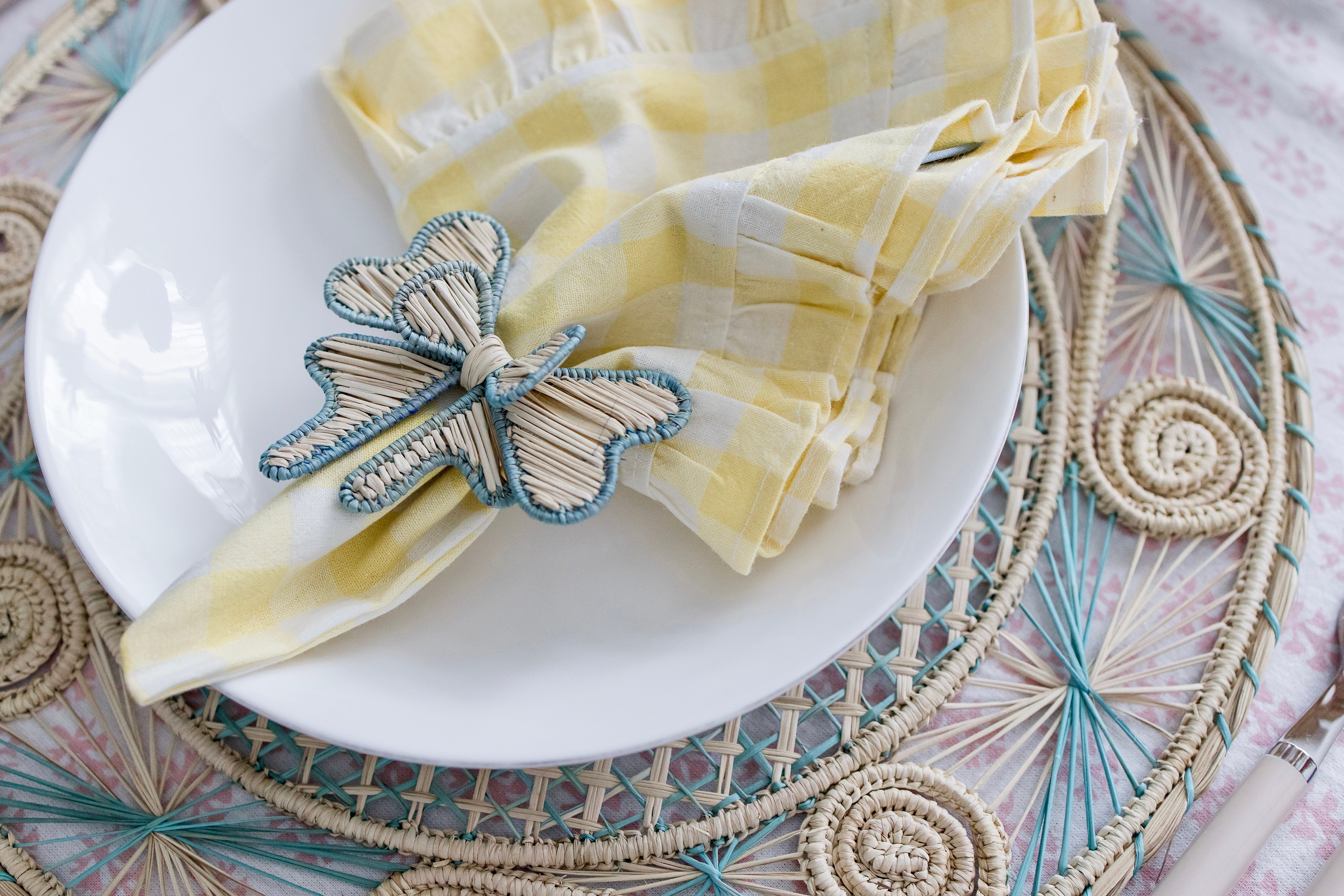 Round handwoven iraca palm placemats in blue adding natural farmhouse texture to a rustic wooden table setting
