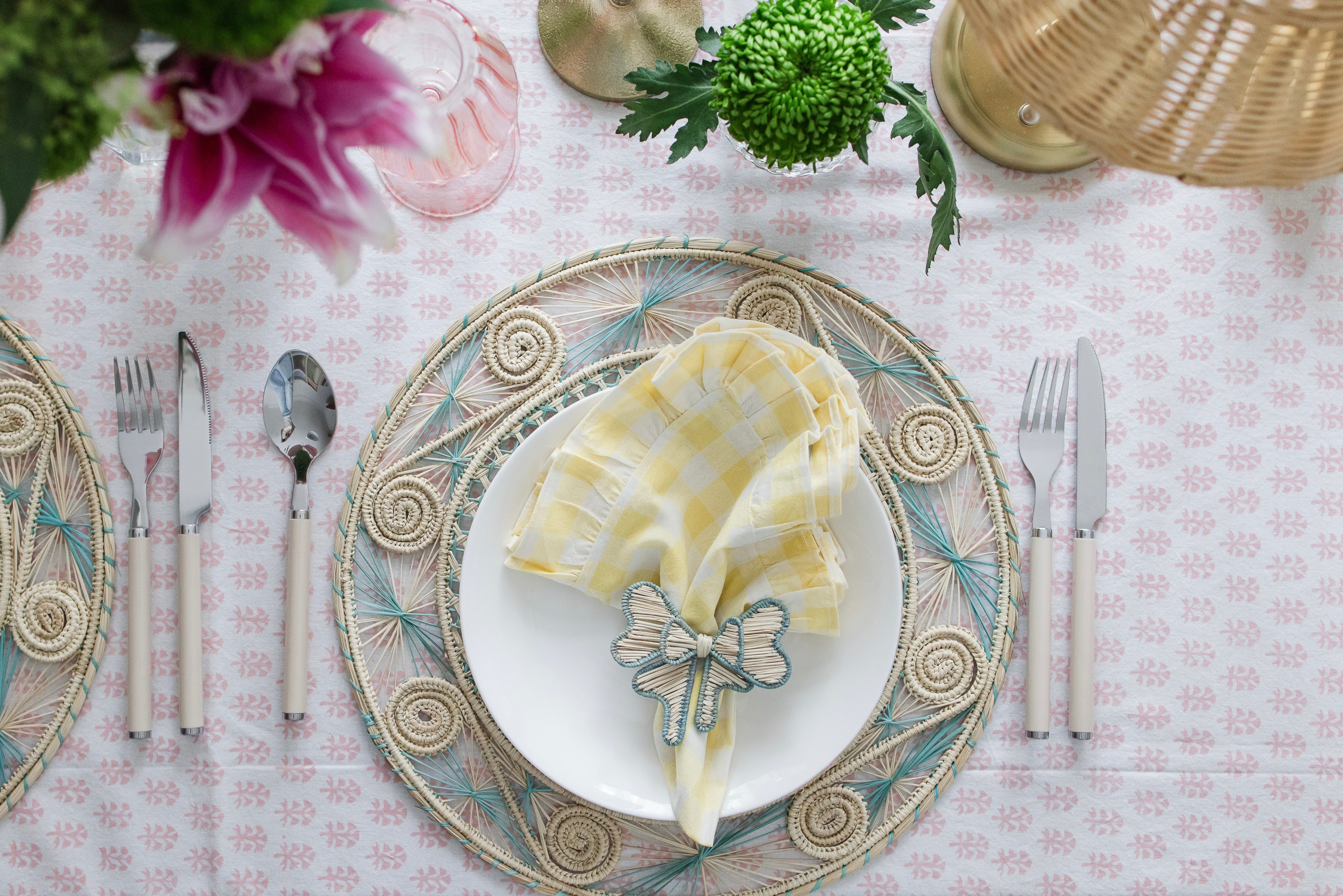 Round handwoven iraca palm placemats in blue adding natural farmhouse texture to a rustic wooden table setting