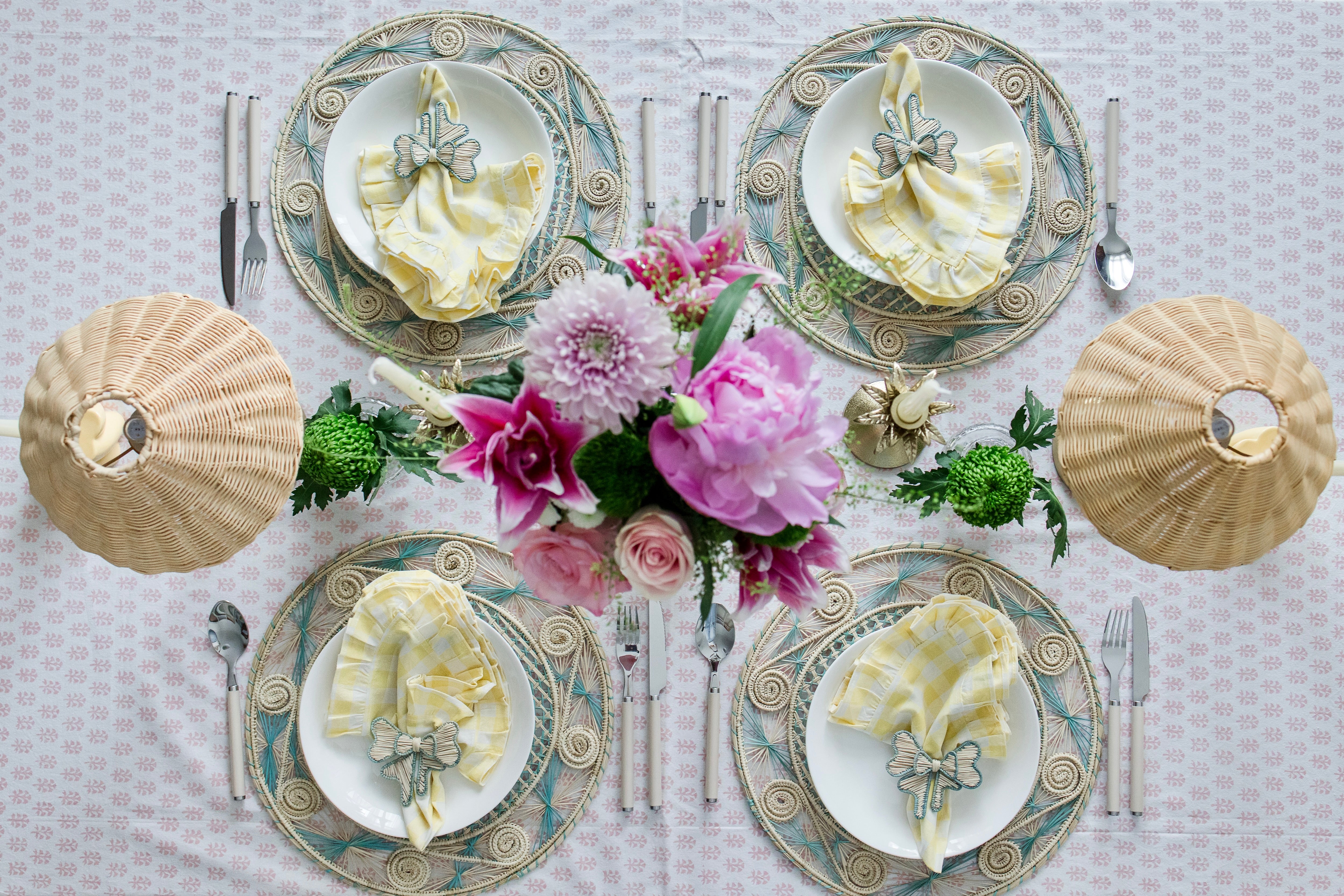 Round handwoven iraca palm placemats in blue adding natural farmhouse texture to a rustic wooden table setting