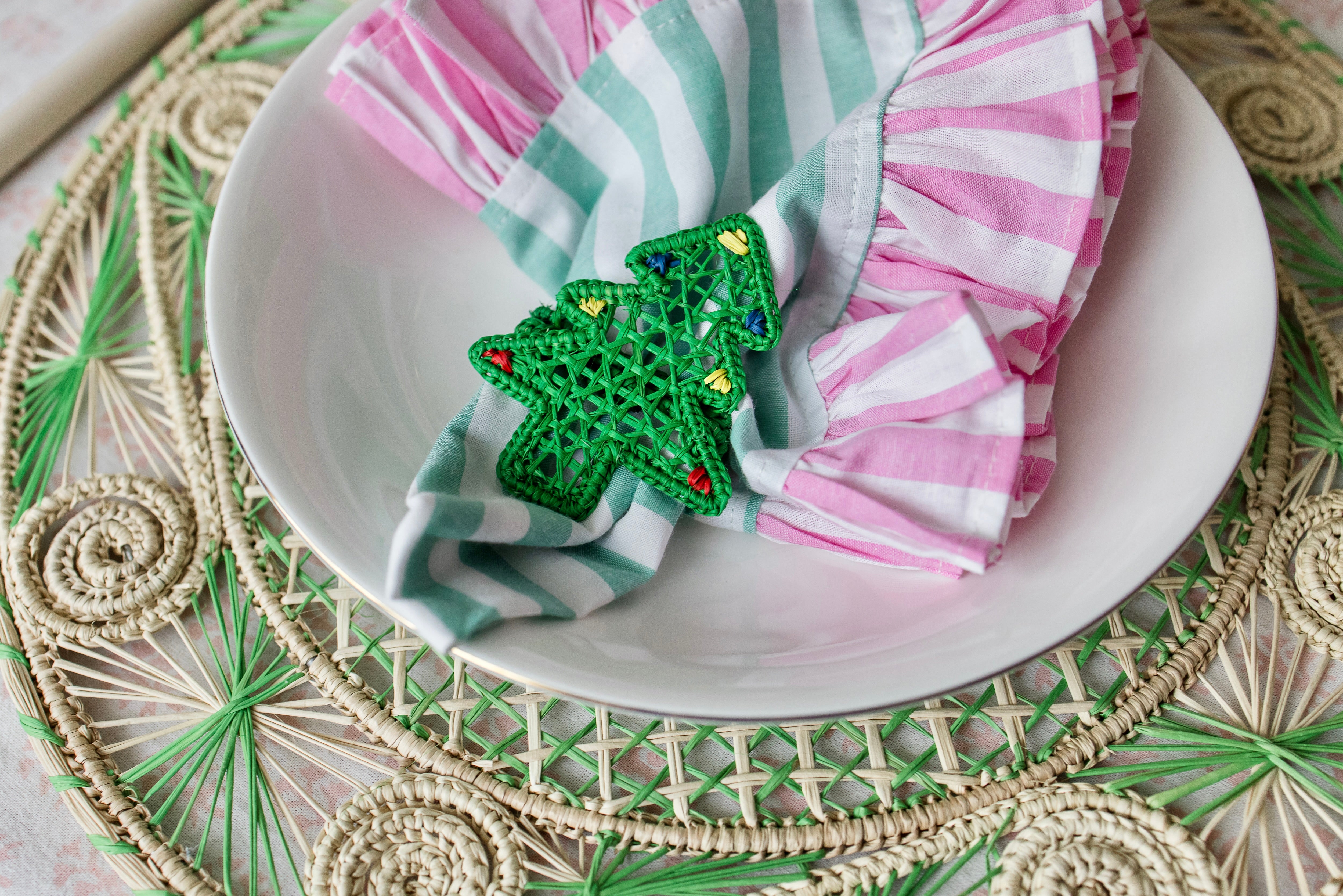 Handcrafted iraca palm christmas napkin rings wrapped around linen napkins on table