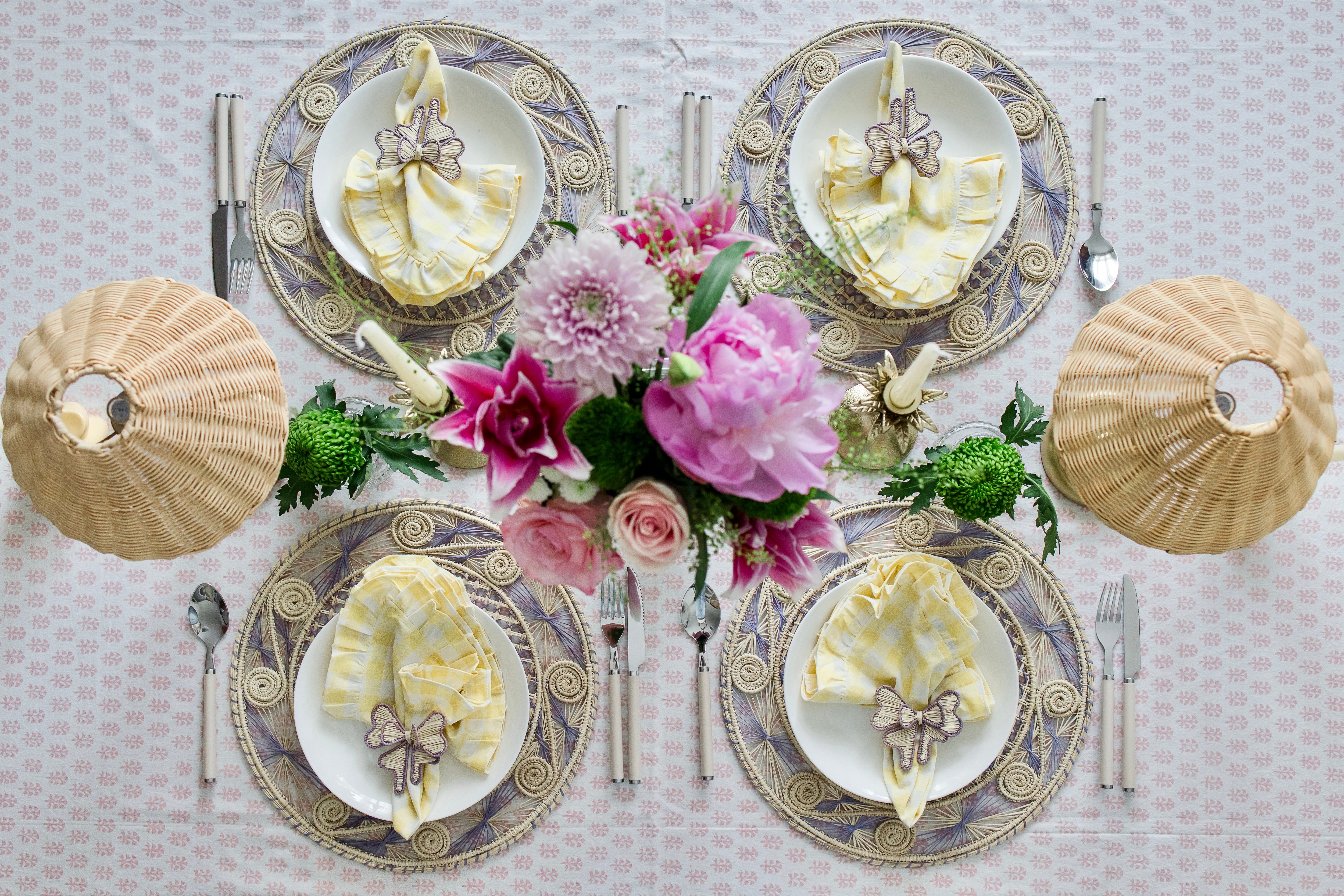 Round handwoven iraca palm placemats in purple lavender adding natural farmhouse texture to a rustic wooden table setting