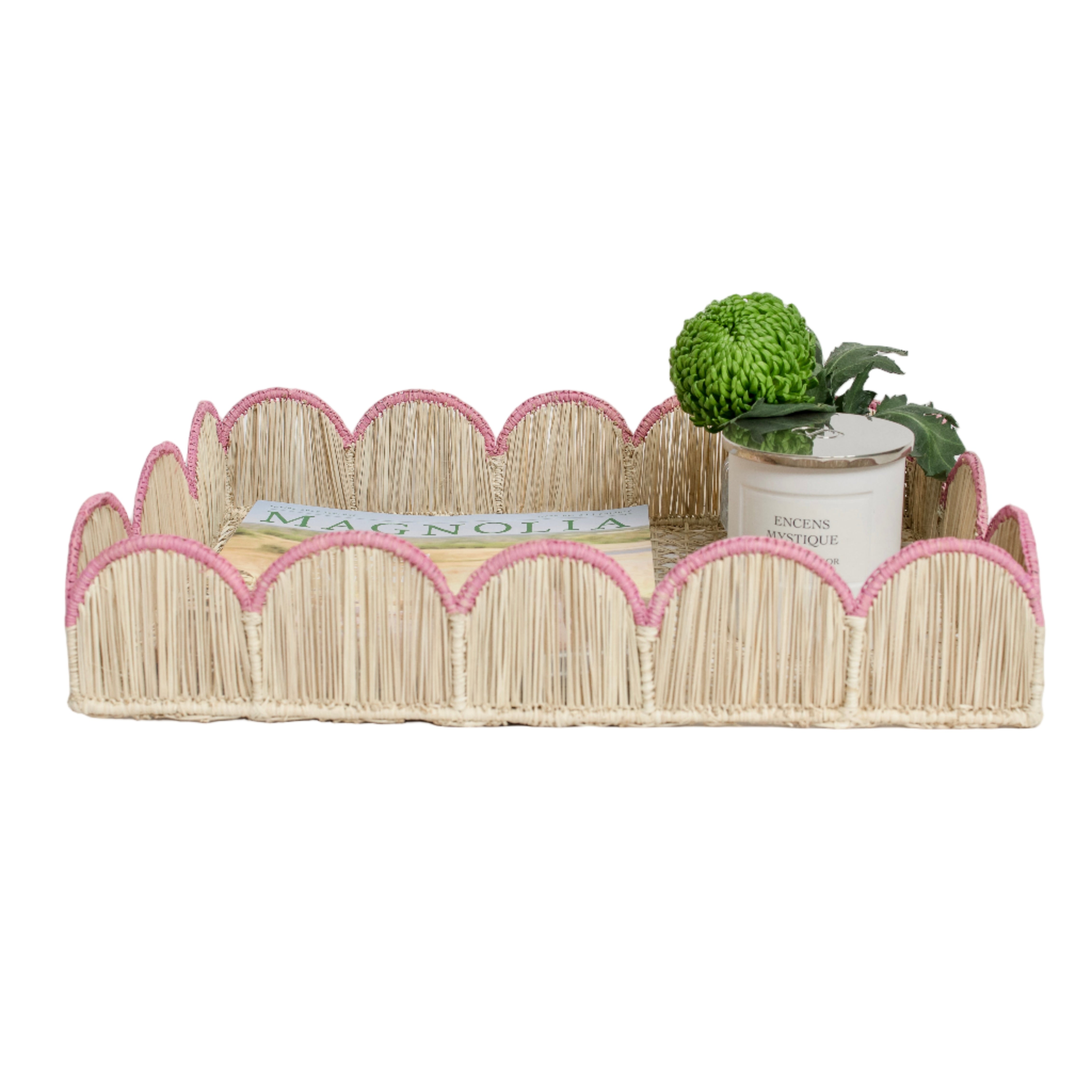 Woven iraca palm serving tray in pink styled with magazine, plant and candle for table decor