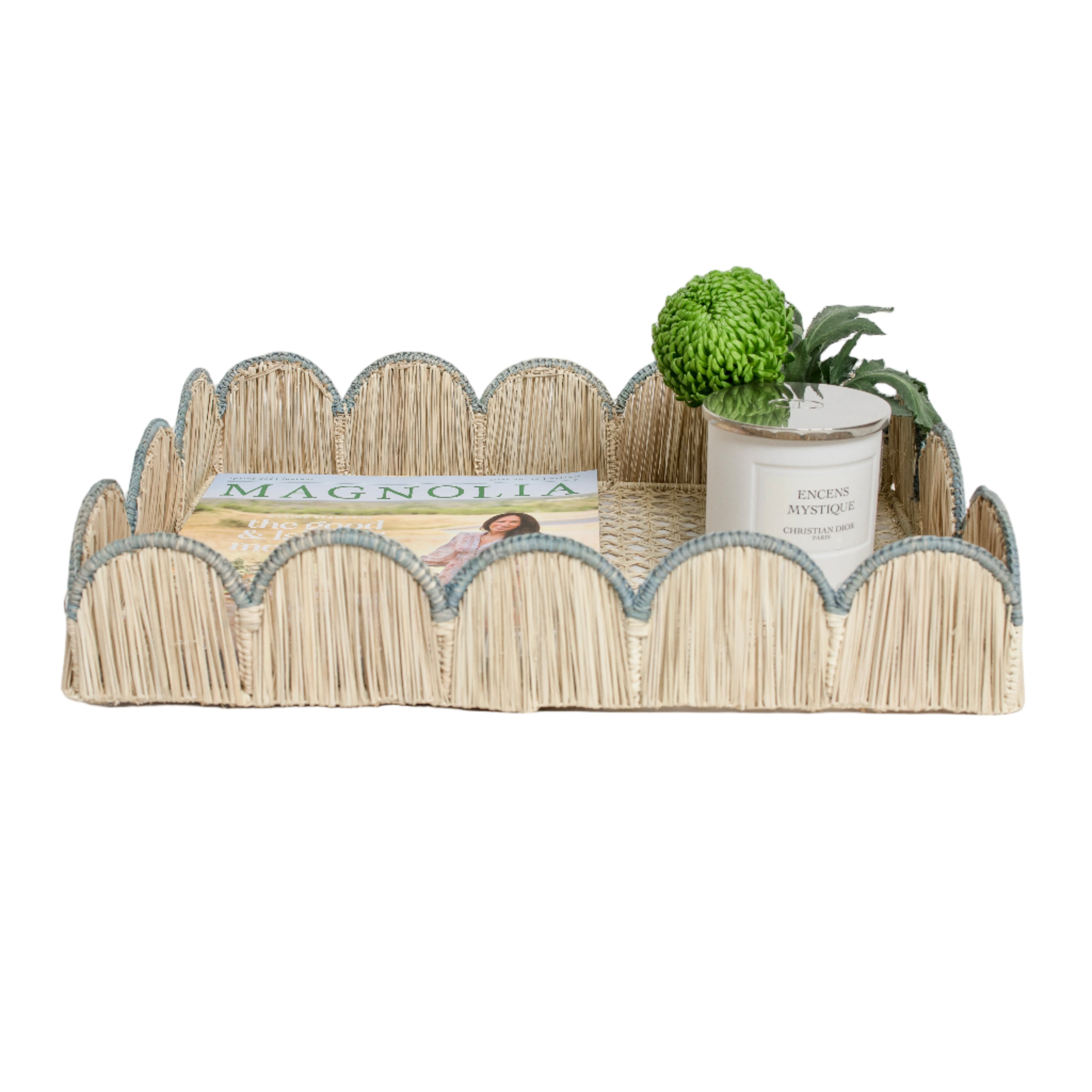 Woven iraca palm serving tray in blue styled with magazine, plant and candle for table decor