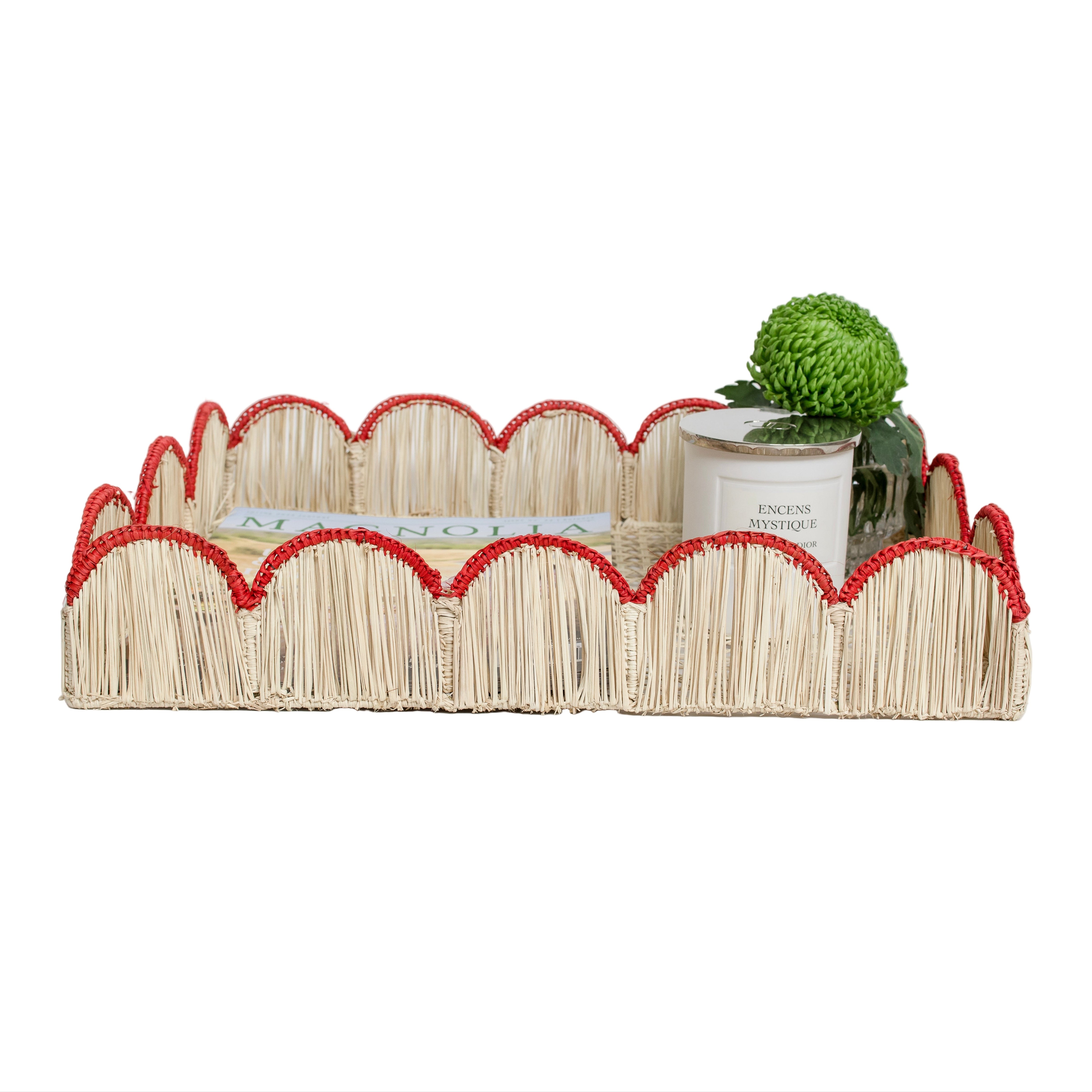 Woven iraca palm serving tray in red styled with magazine, plant and candle for table decor