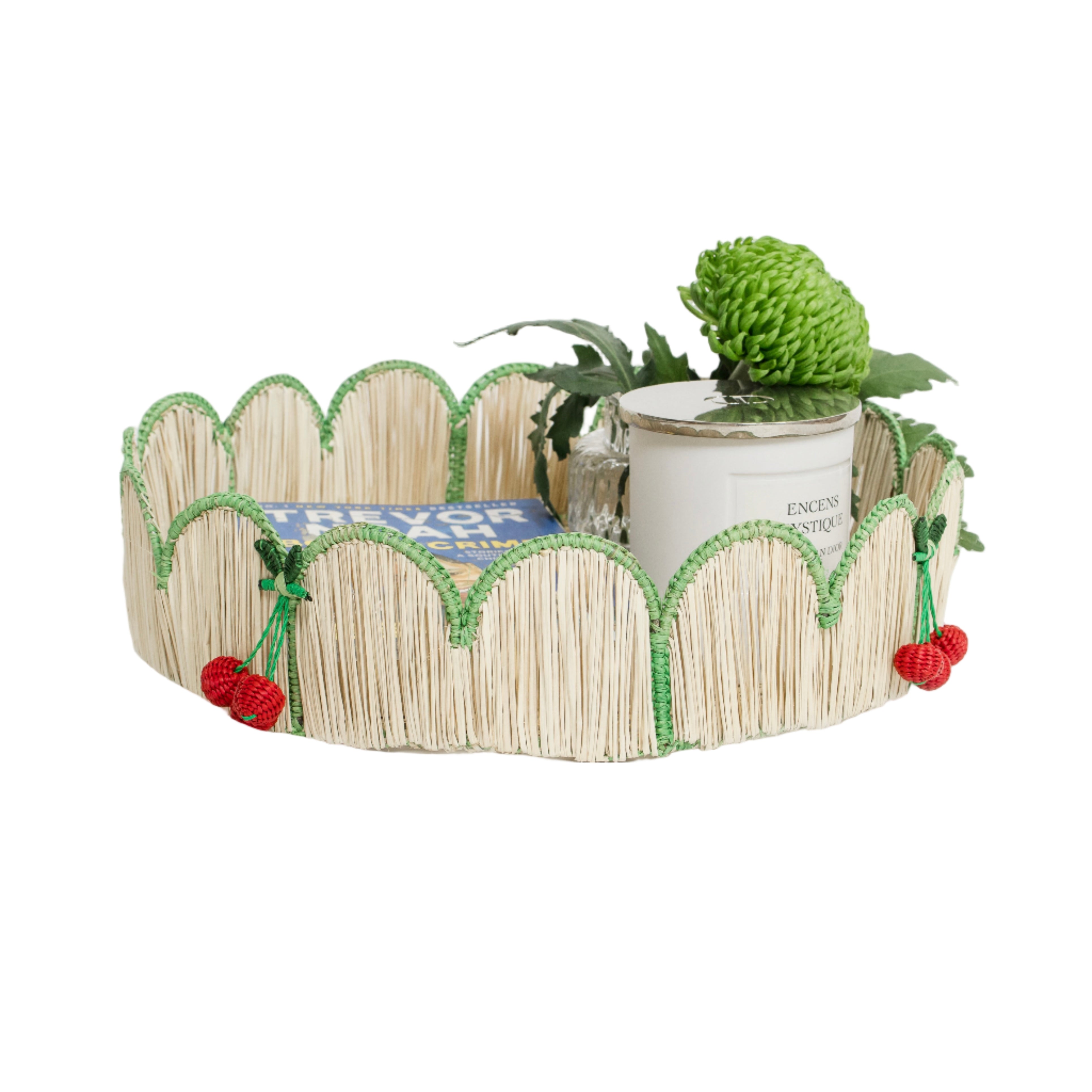 Woven iraca palm round scallop tray with cherries styled with magazine, plant and candle for table decor