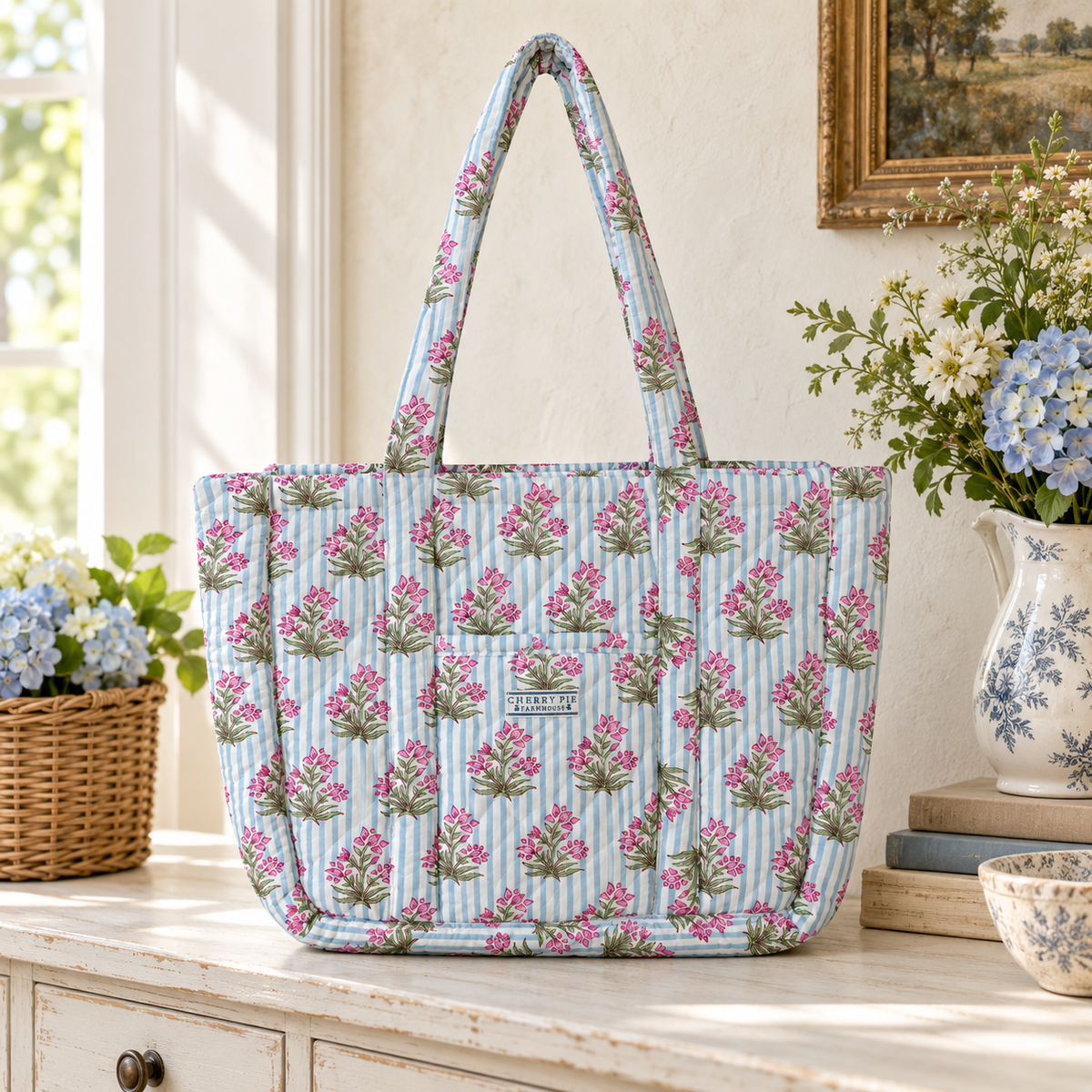 Pale blue striped quilted floral tote bag styled on a whitewashed console in a country interior.