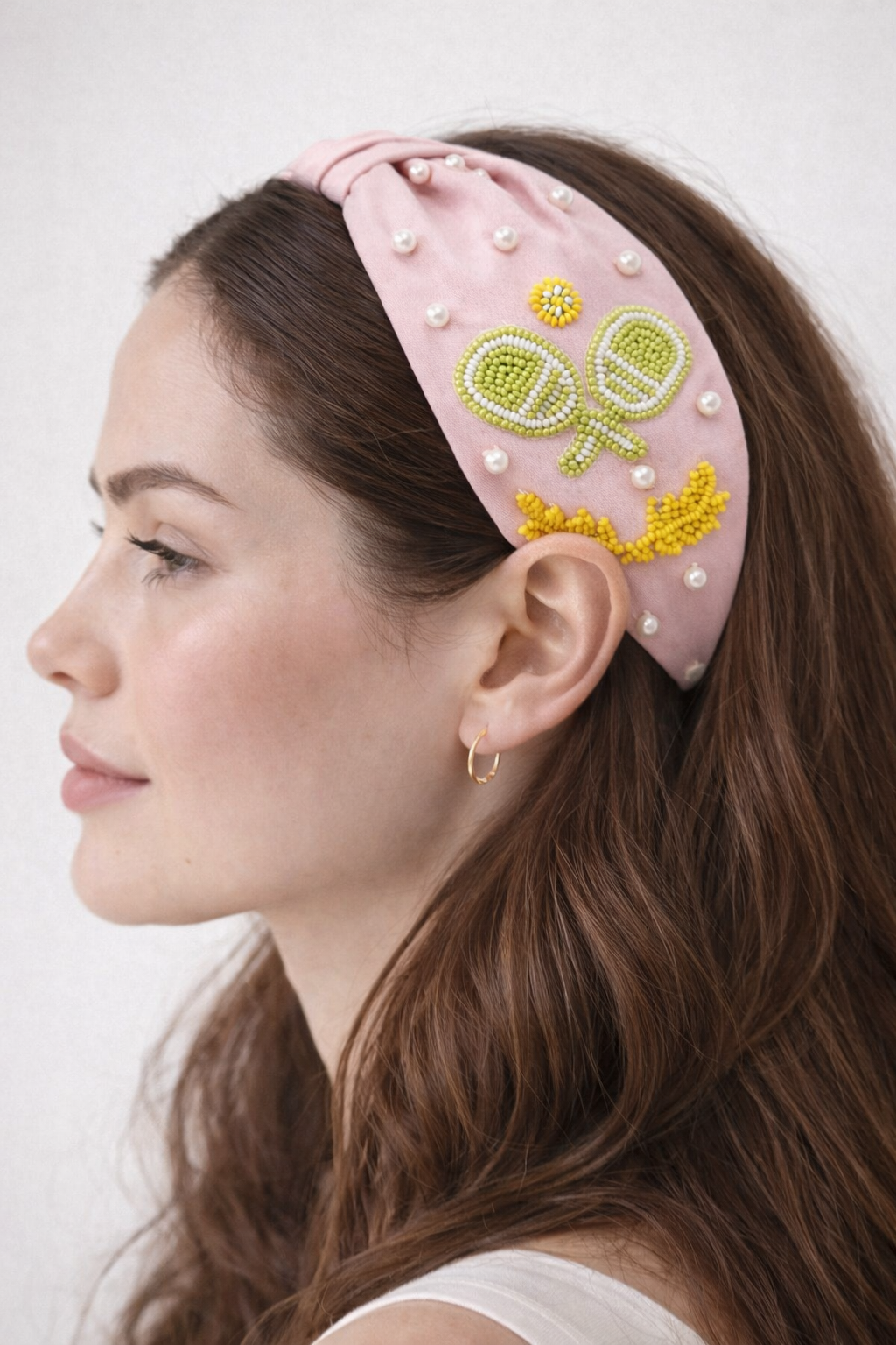 Woman wearing a pink headband with pickleball design on a white background