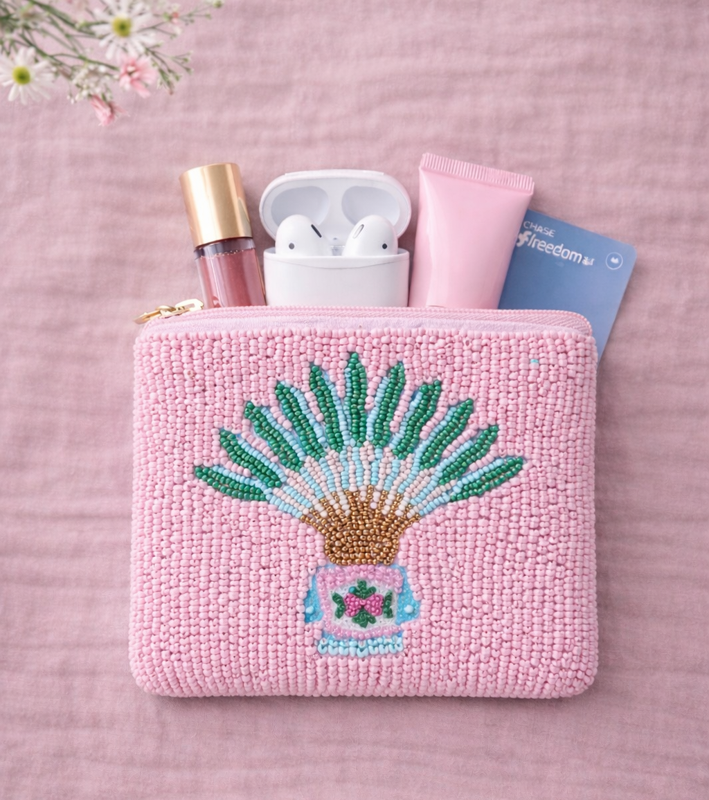 Pink pouch with embroidered traveller palm and peranakan motif design on a pink background