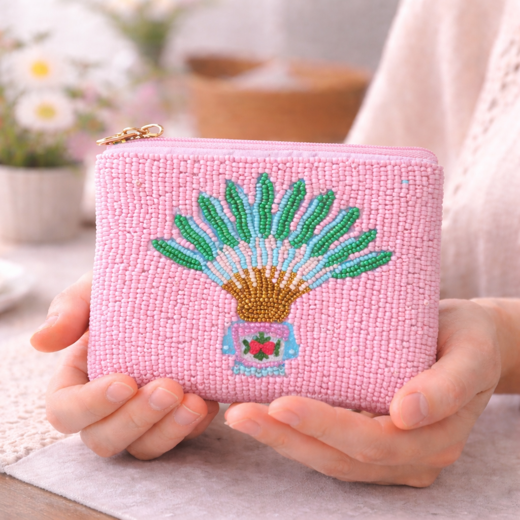Pink beaded pouch with traveller palm and peranakan motif design held by a person.