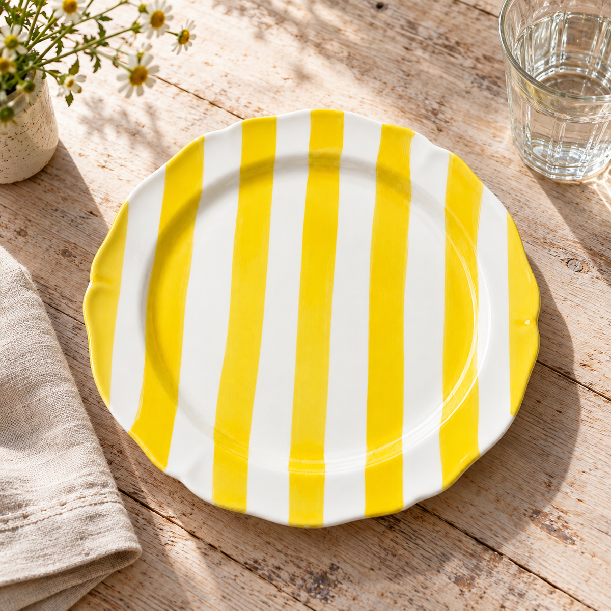 Yellow striped hand-painted ceramic plate styled on a sunlit farmhouse table